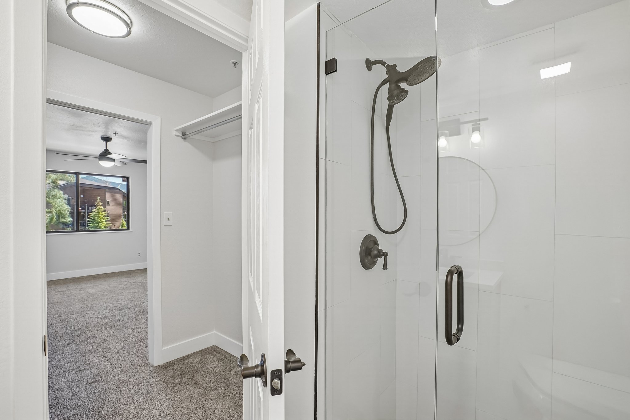 Shower enclosure featuring a frameless glass door, dark bronze fixtures, and white tile surround
