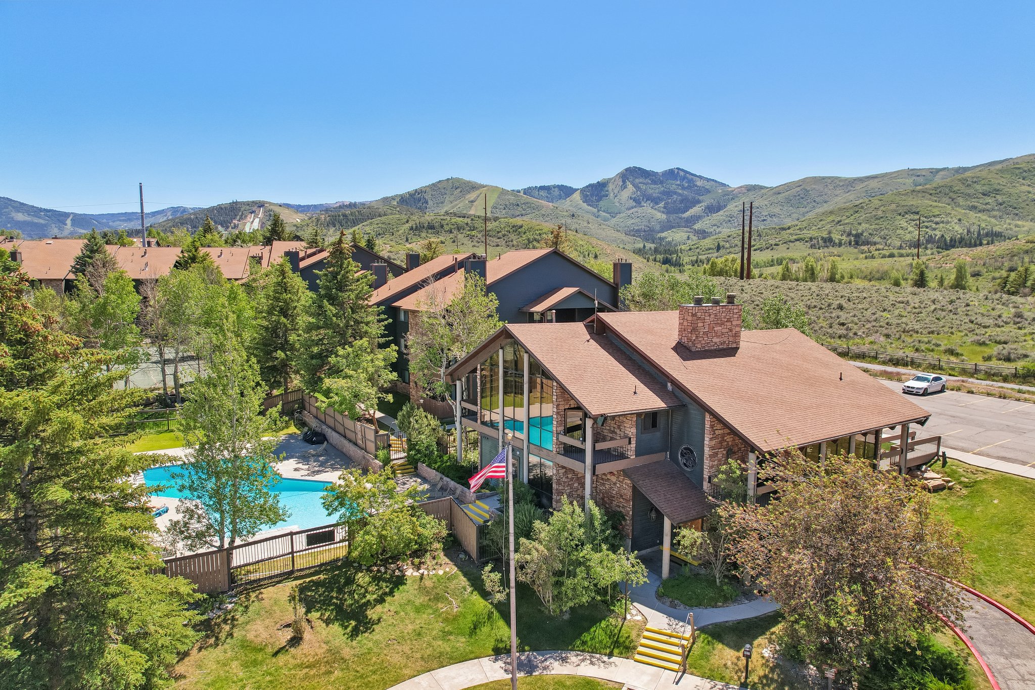 Stone-clad exterior with a prominent chimney, large windows, and an expansive mountain backdrop