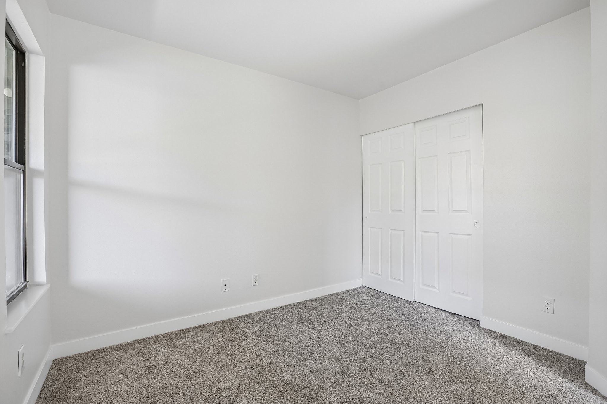 Room featuring plush gray carpet, white painted walls, white baseboards, and a window with a white sill