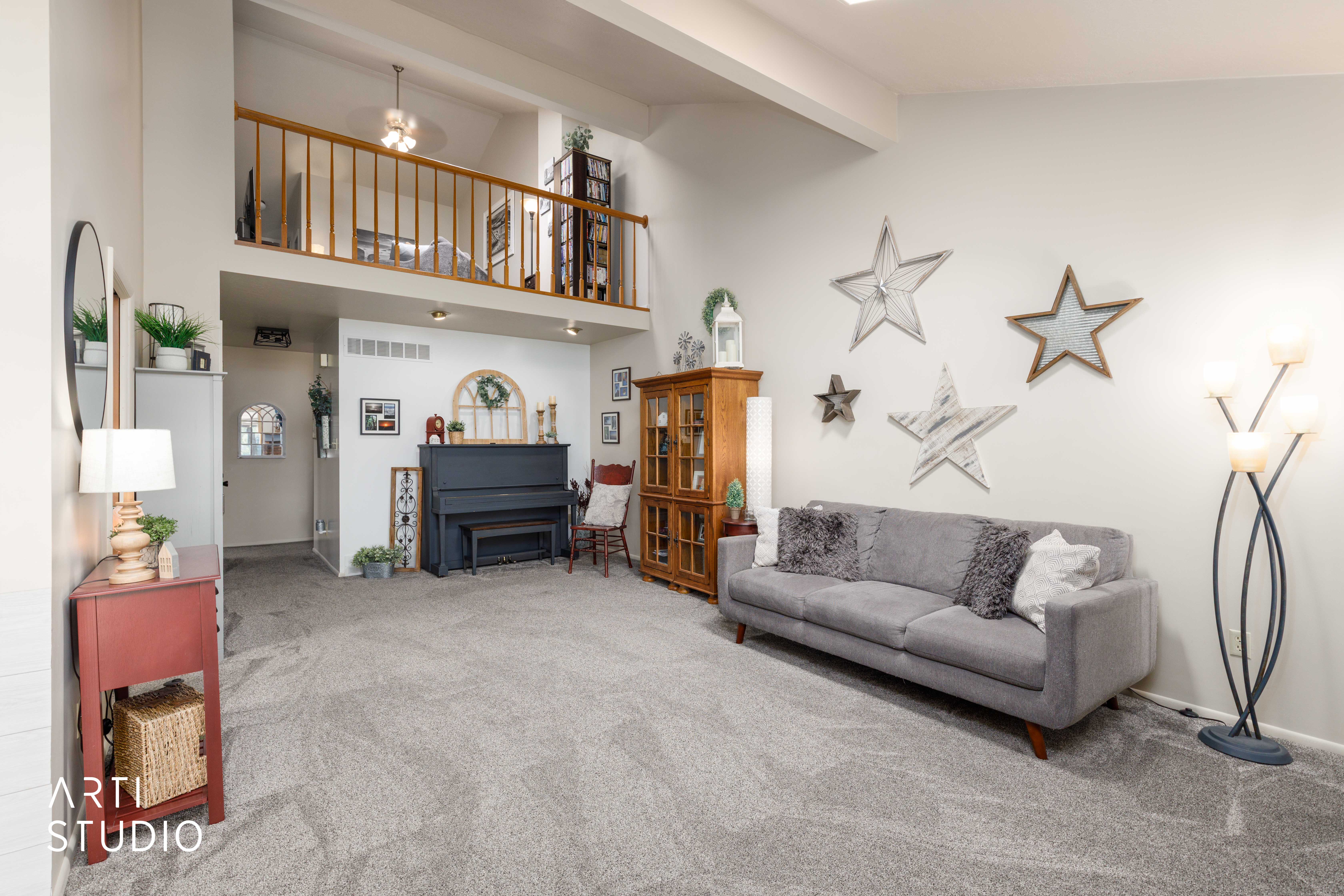 Vaulted ceilings and an open-concept layout define this living space, featuring a second-story loft with wood railing overlooking the room
