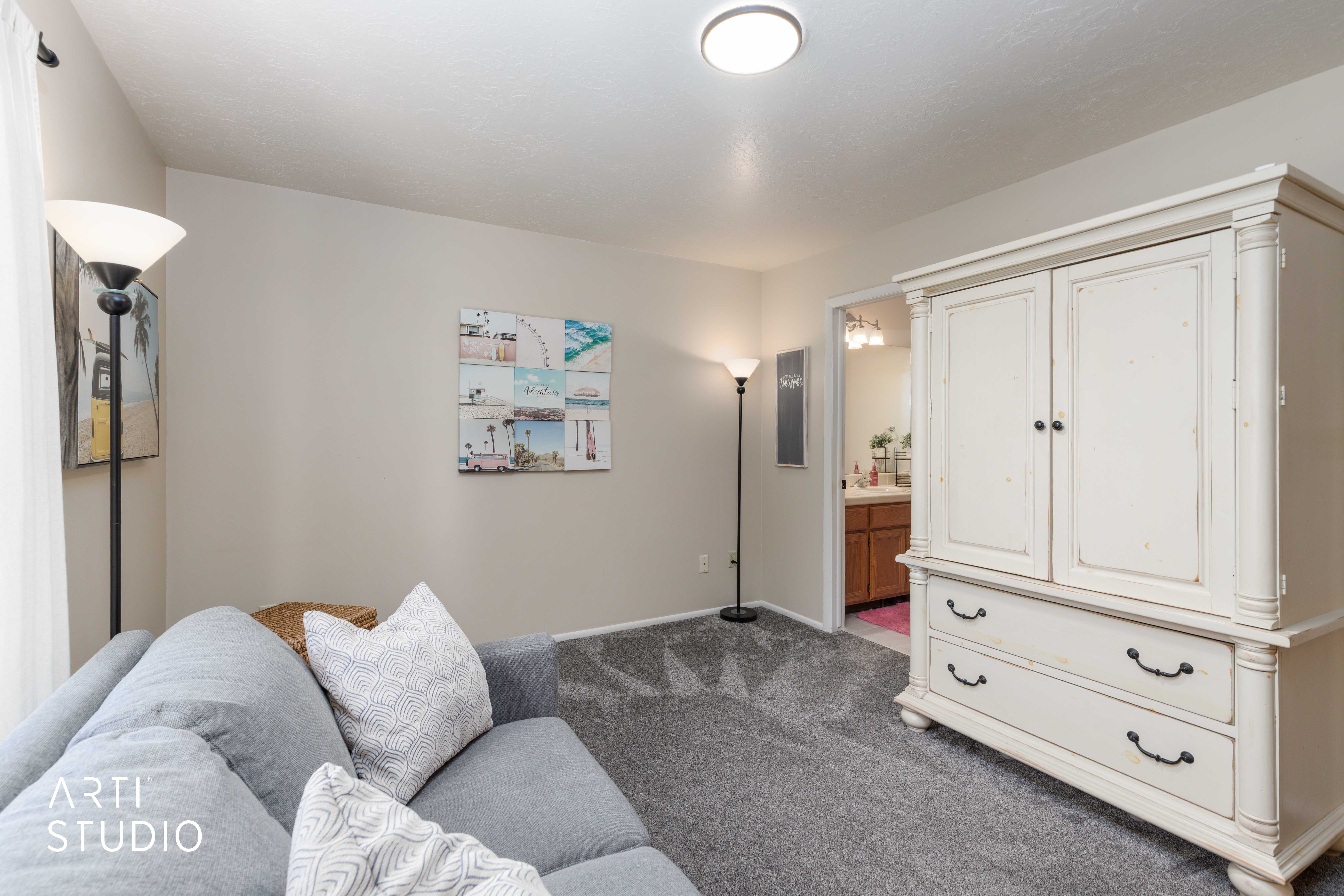 Wall-to-wall gray carpeting, light neutral wall paint, and a flush-mount ceiling light fixture