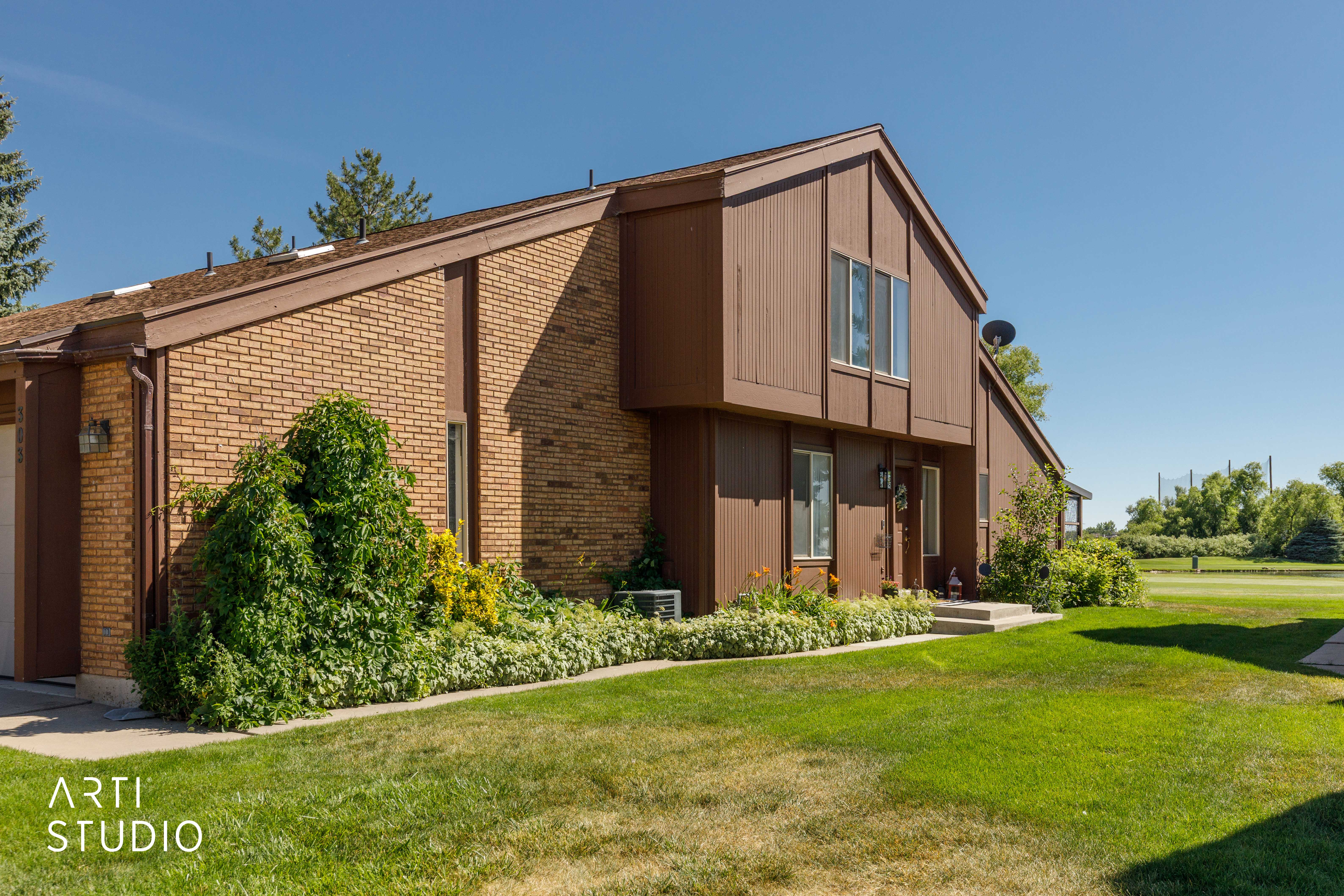 Brick and wood-sided exterior featuring a pitched roofline and manicured landscaping