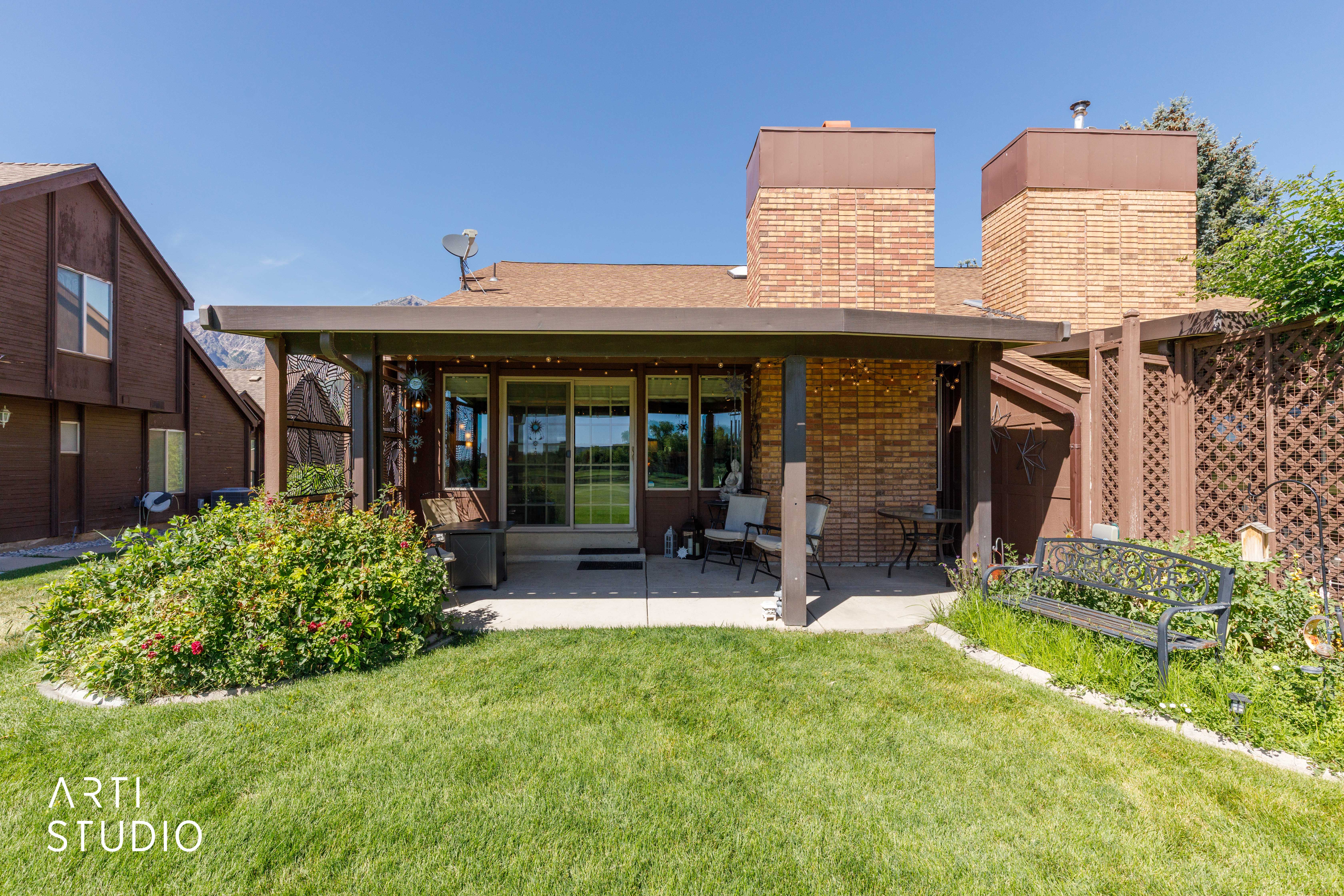 Covered patio with a concrete surface, featuring brick siding, a sliding glass door, and a lattice privacy screen