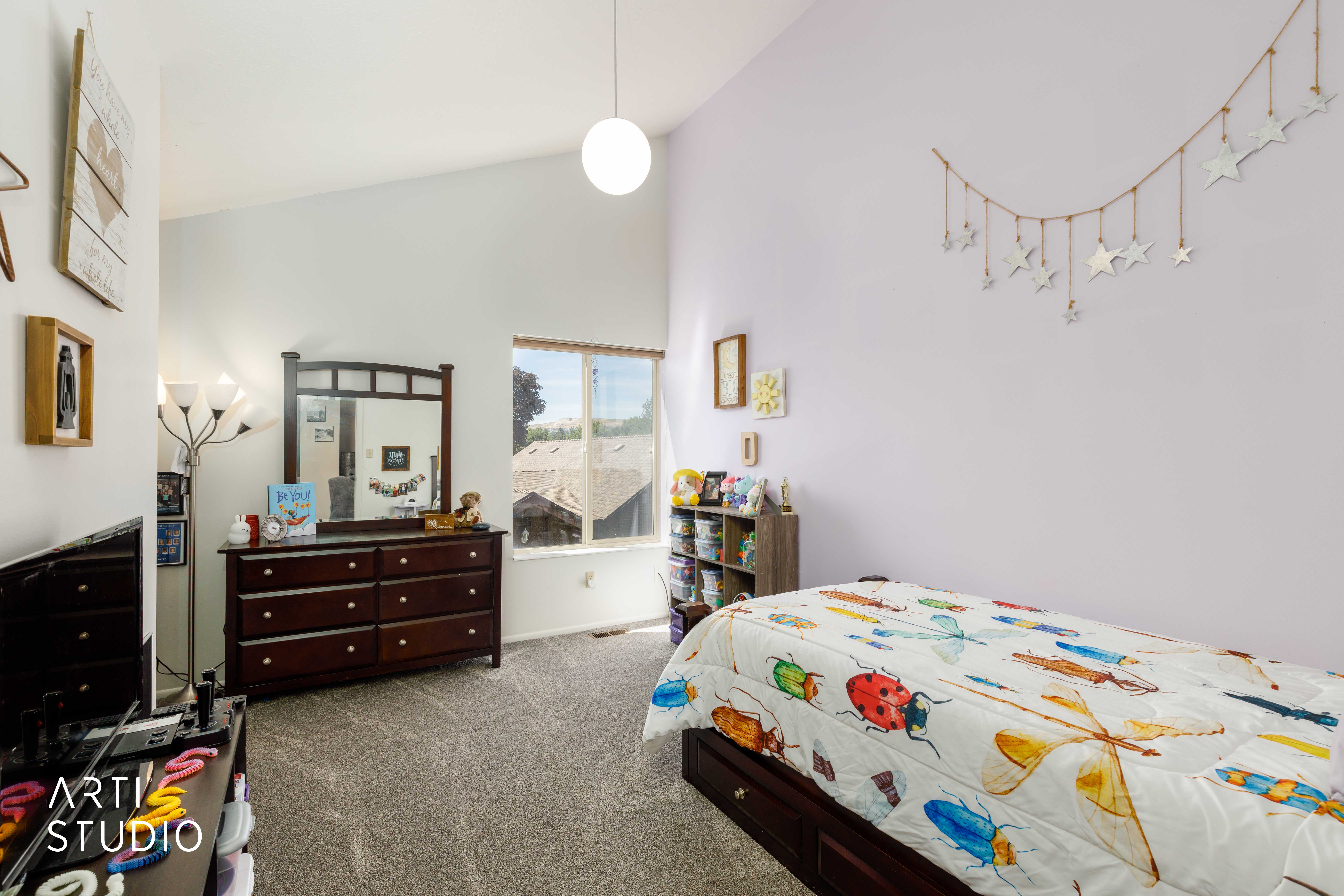 Carpeted room featuring a vaulted ceiling with a spherical pendant light, a large window, and a built-in storage bed