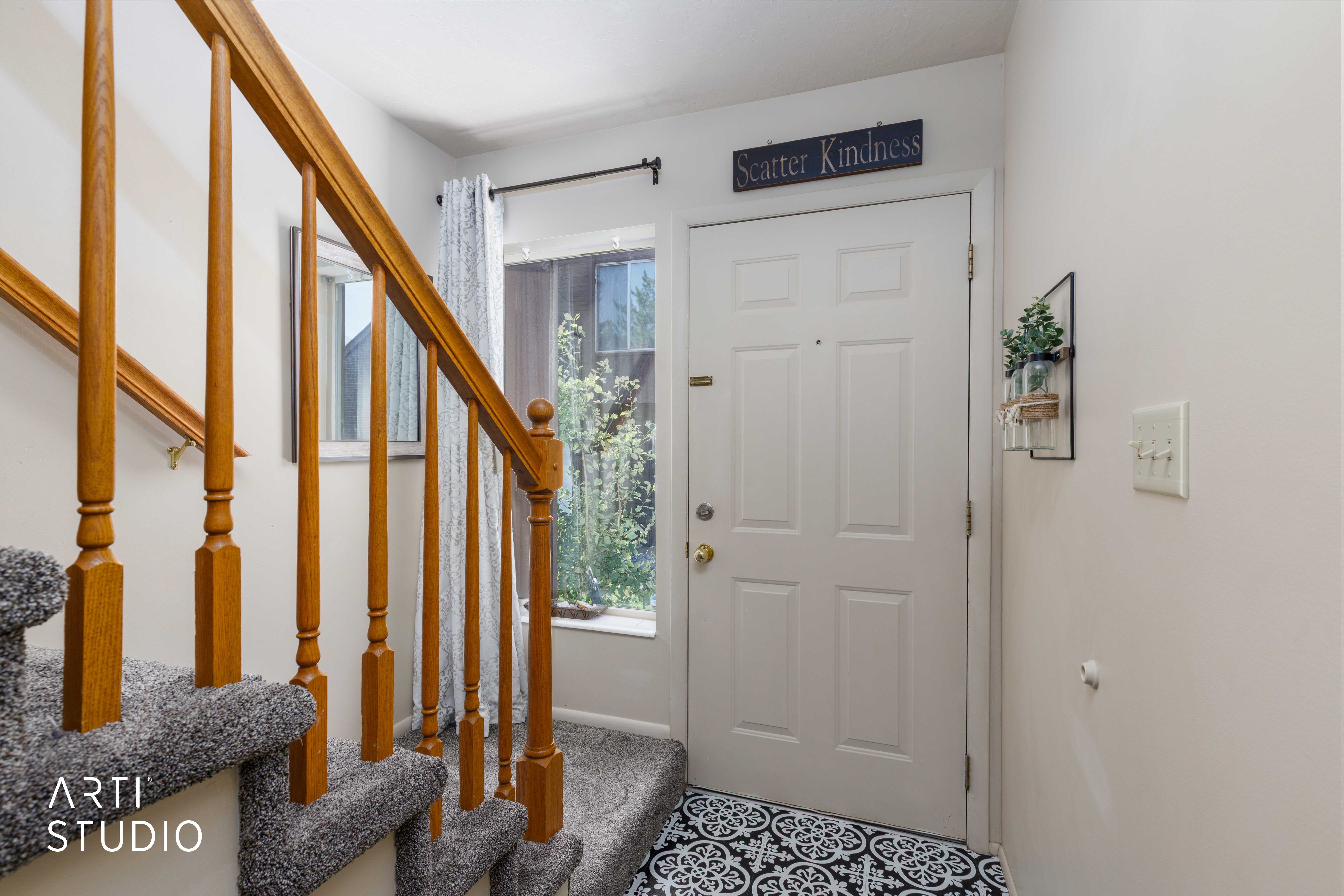 Entryway featuring a paneled door, patterned floor tile, and a staircase with wood-finish railings and carpeted treads
