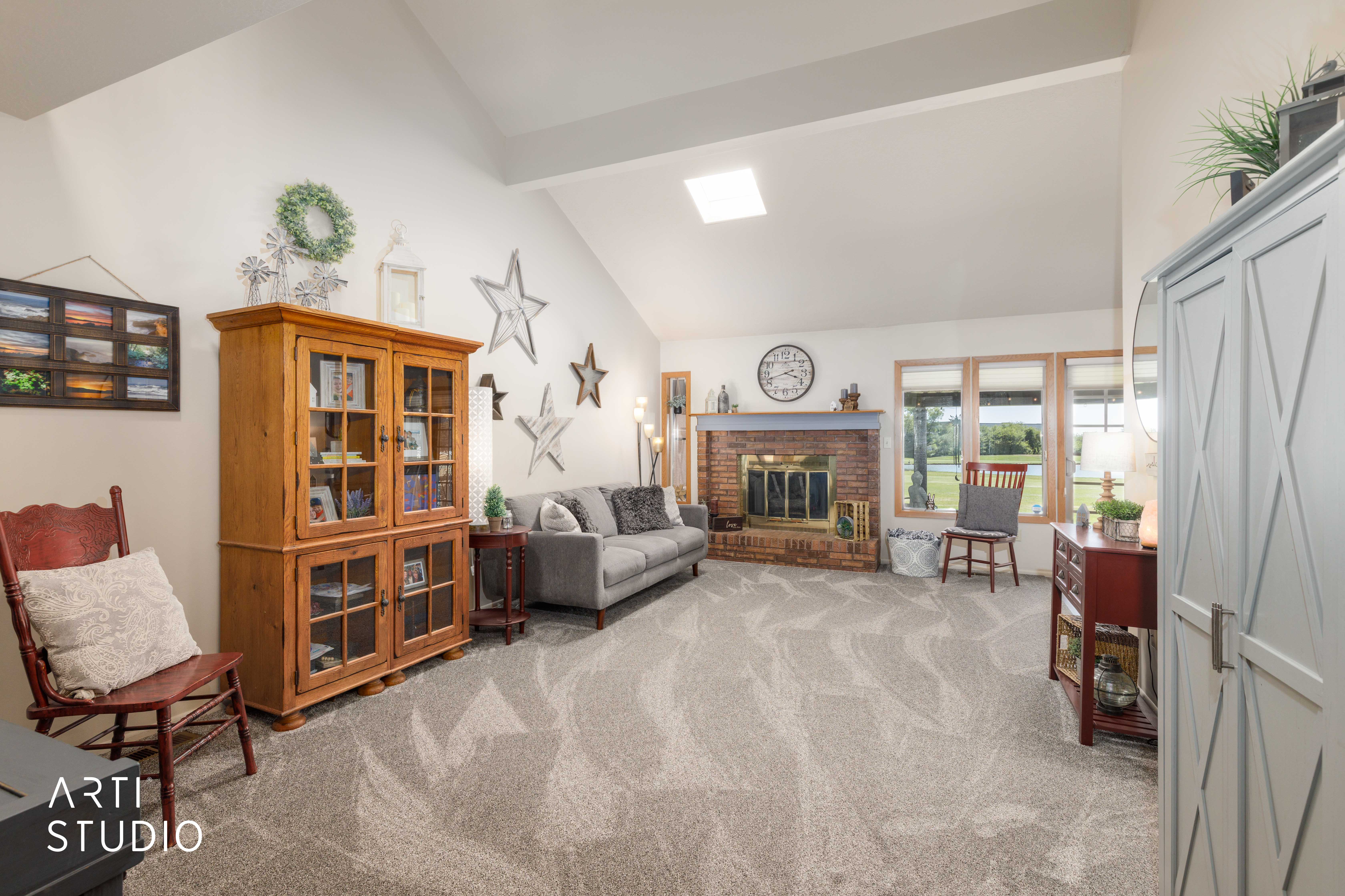 Spacious room featuring vaulted ceilings, a brick fireplace, a skylight, and large windows