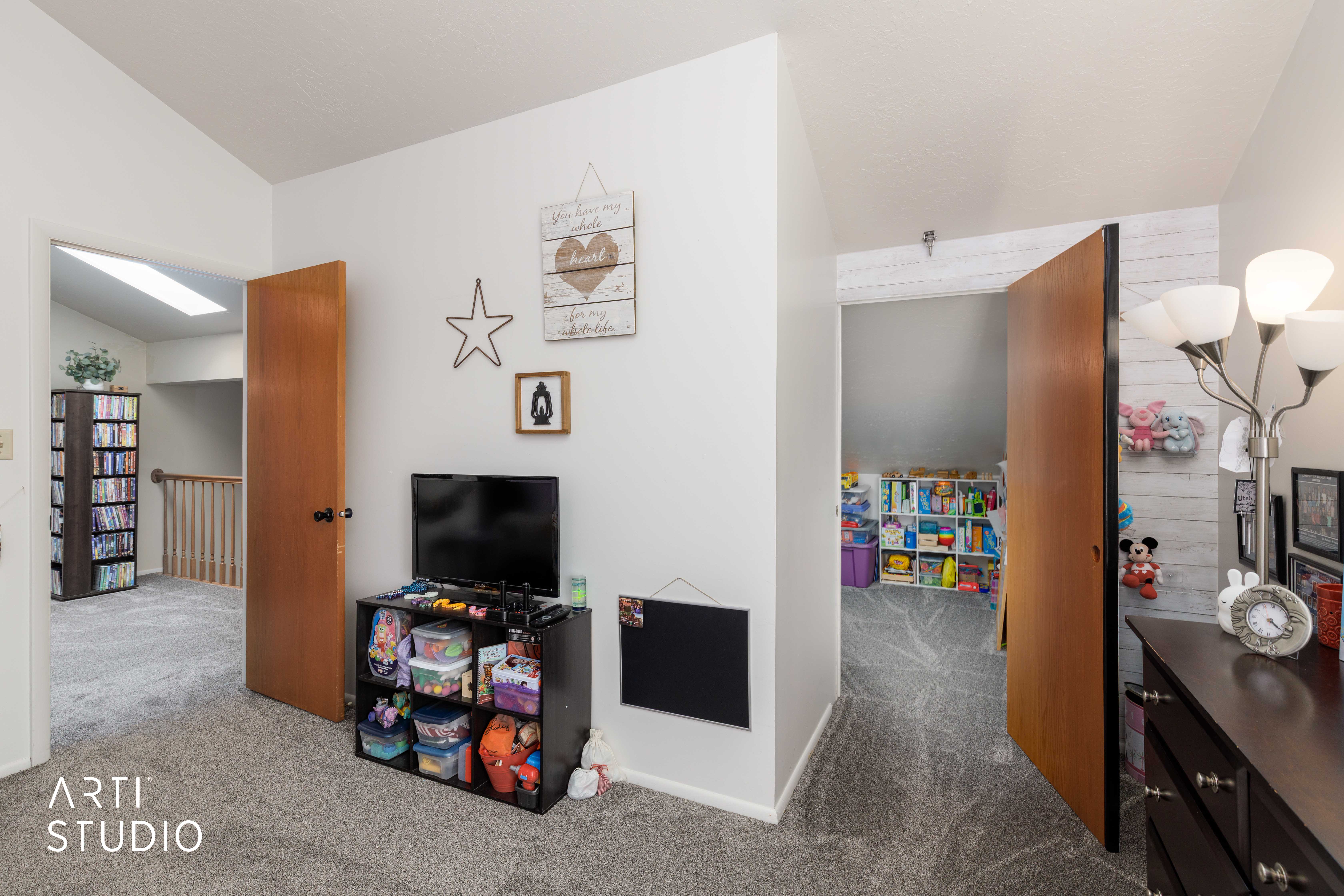 Carpeted hallway with white walls and a vaulted ceiling