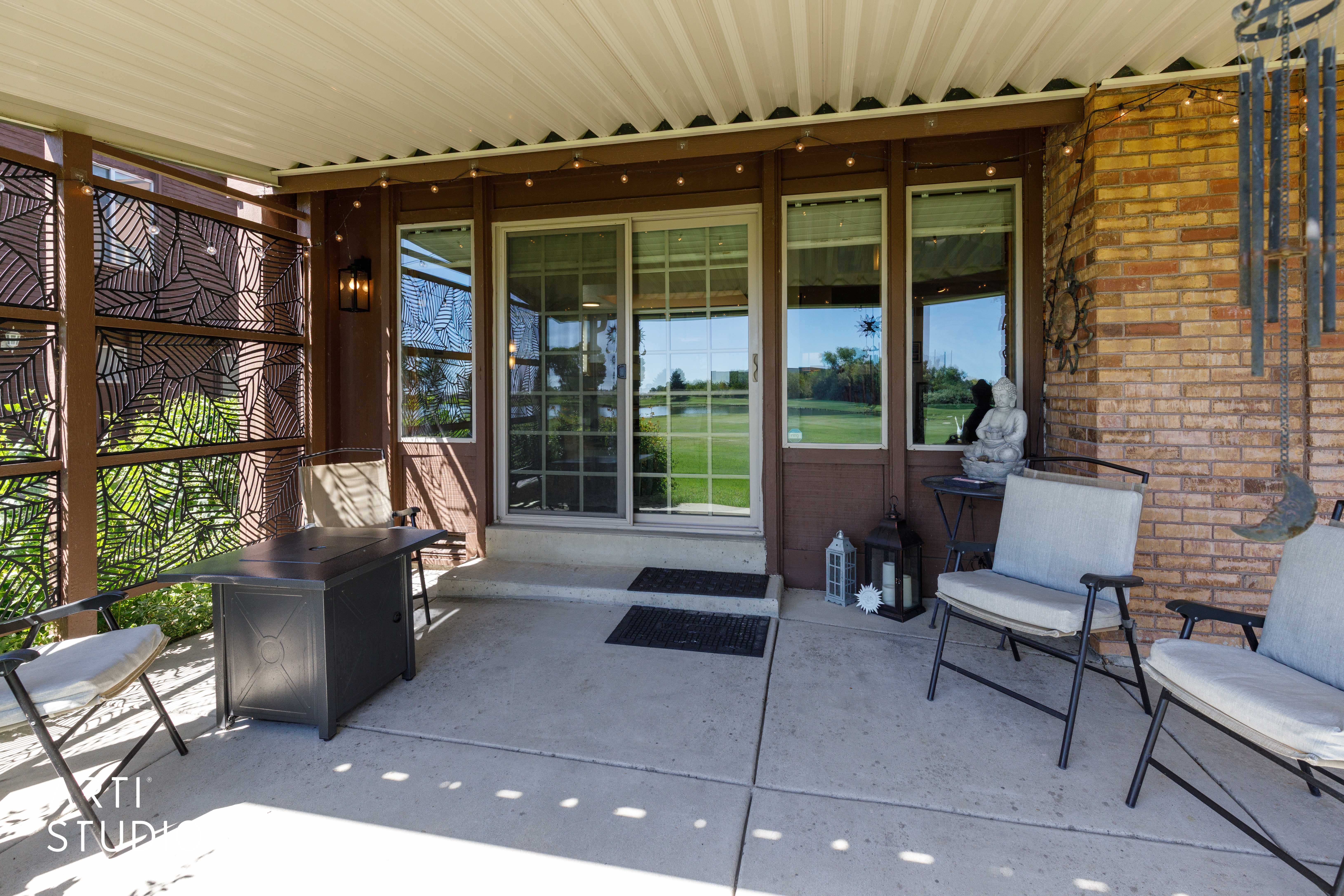 Covered patio featuring a concrete slab, a brick exterior wall, and a wood-finish privacy screen with geometric cutouts