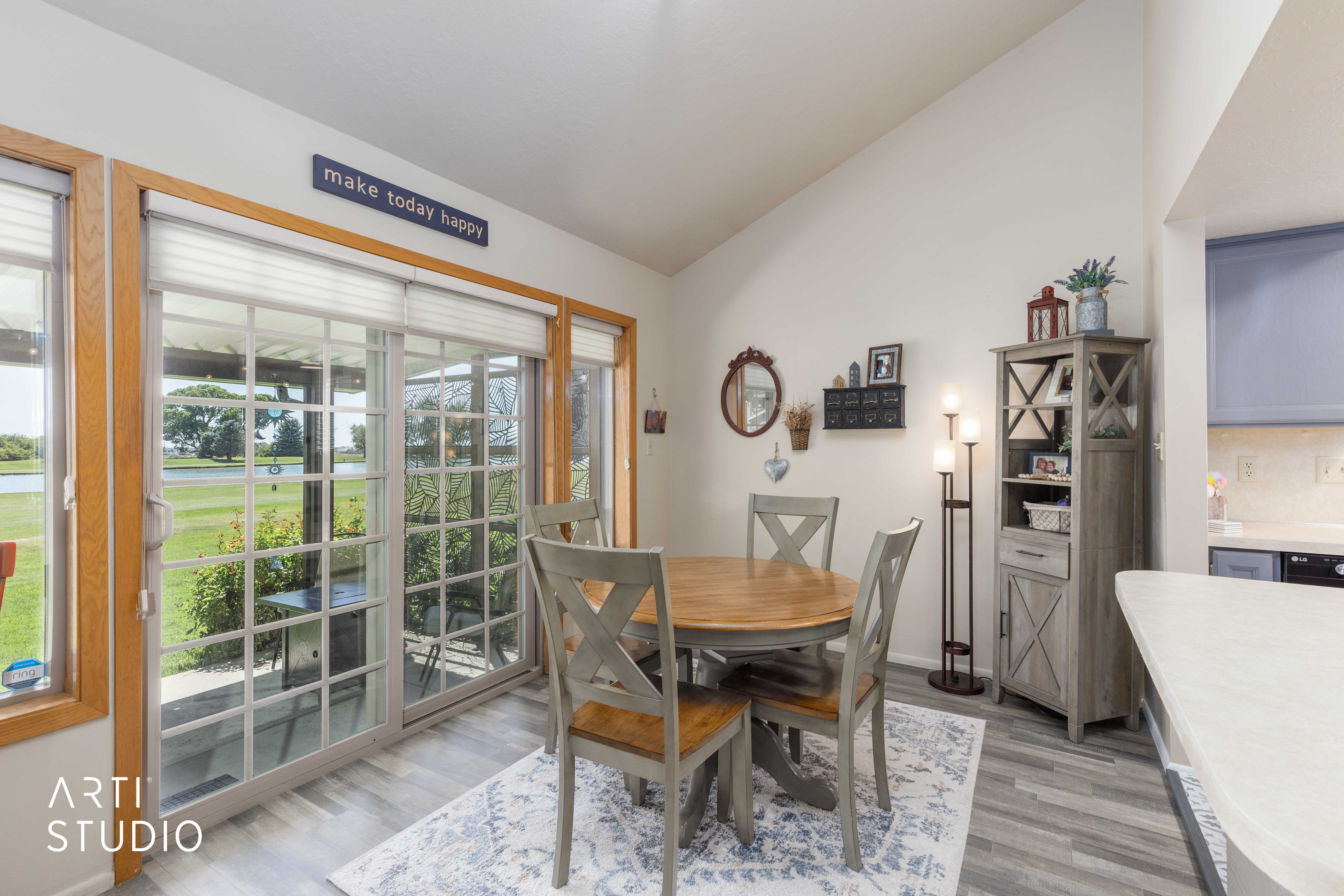 Vaulted ceiling dining area featuring wood-finish flooring and ample natural light through extensive sliding glass doors