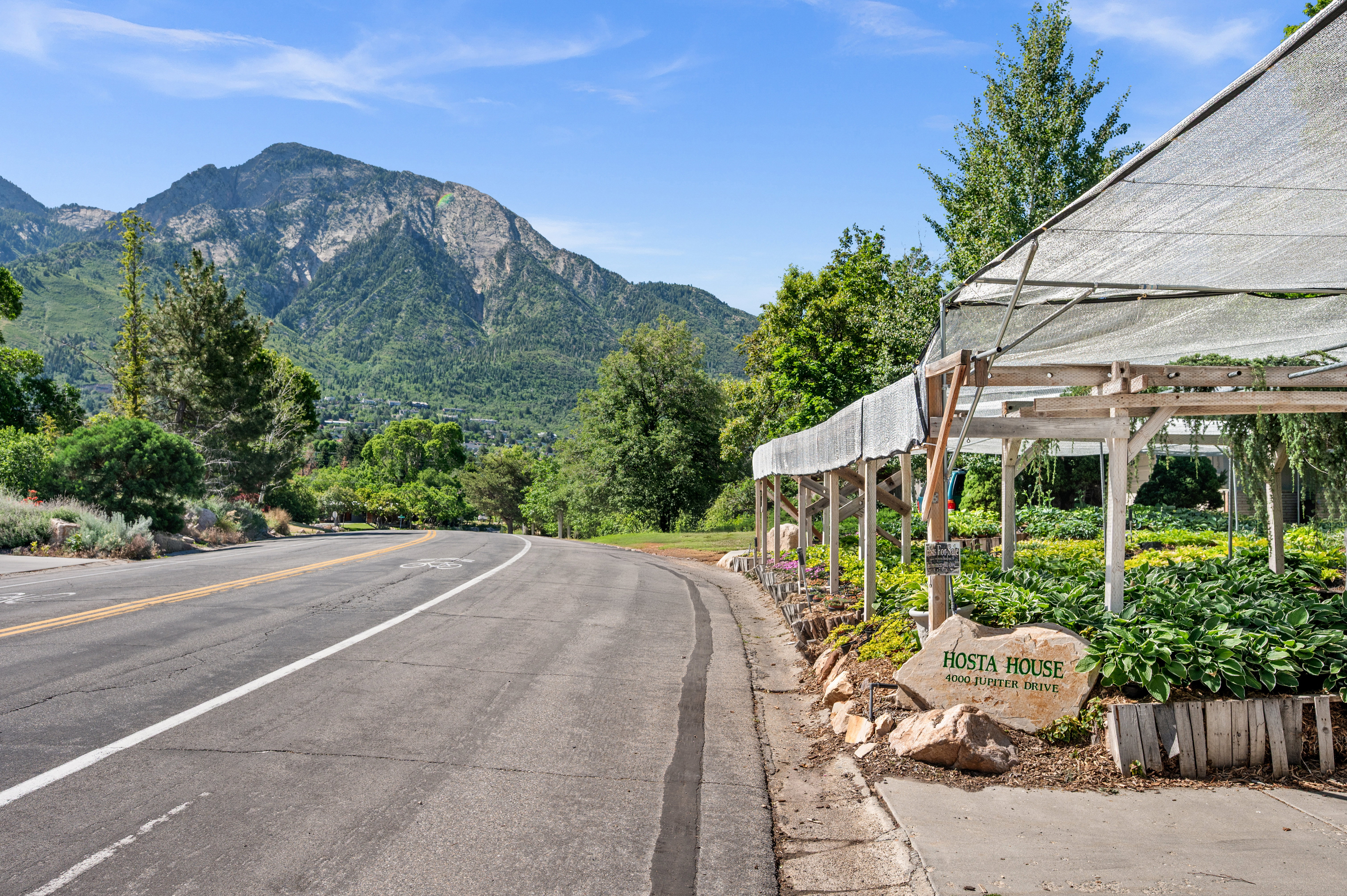 Expansive plant nursery featuring a shade structure, mature greenery, and a prominent "Hosta House" sign