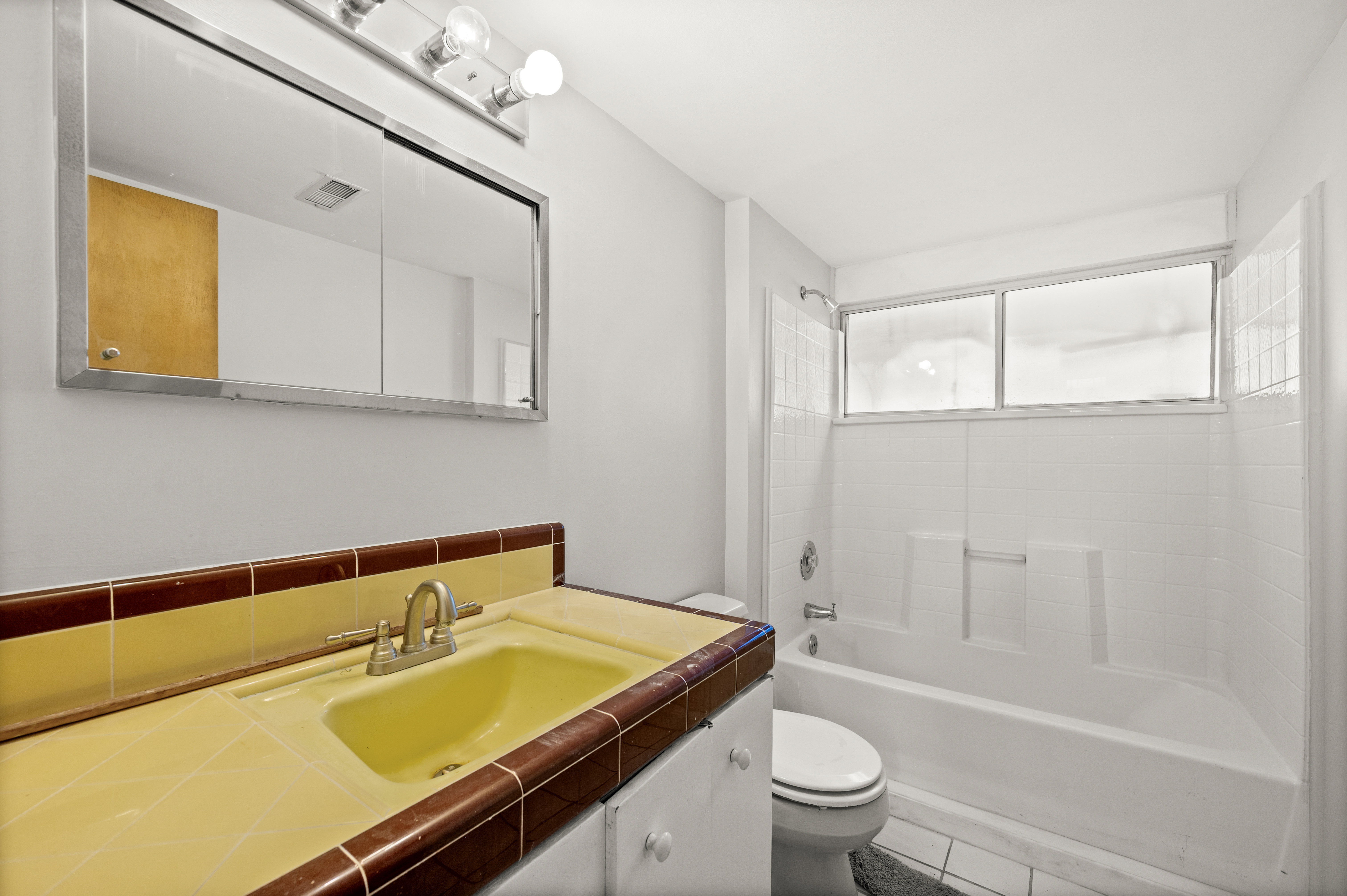 Bathroom featuring a tiled vanity with integrated sink, chrome faucet, and mirrored medicine cabinet
