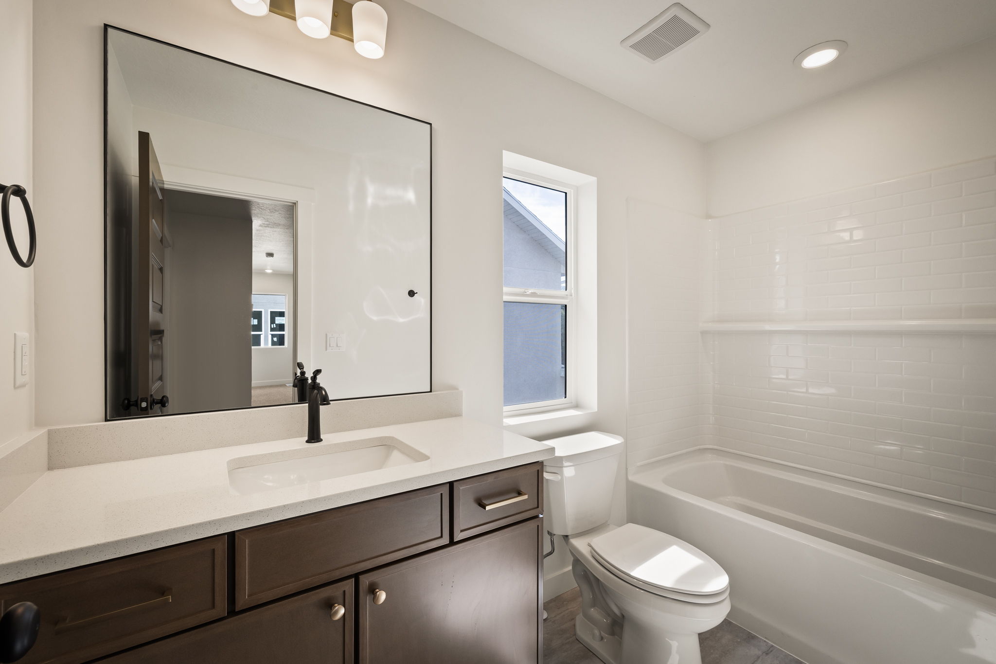 Bathroom featuring a dark wood-finish vanity with a light-toned countertop, a rectangular undermount sink, and a black-framed mirror