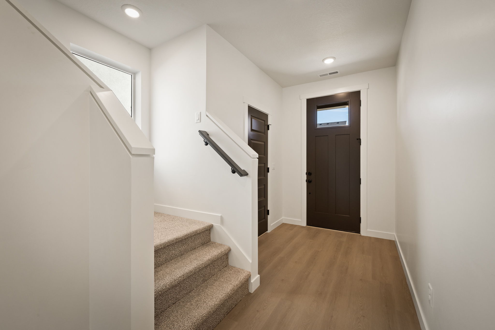Entryway featuring a dark wood-finish front door with an upper window pane, wood-finish flooring, recessed lighting, and a neutral color palette