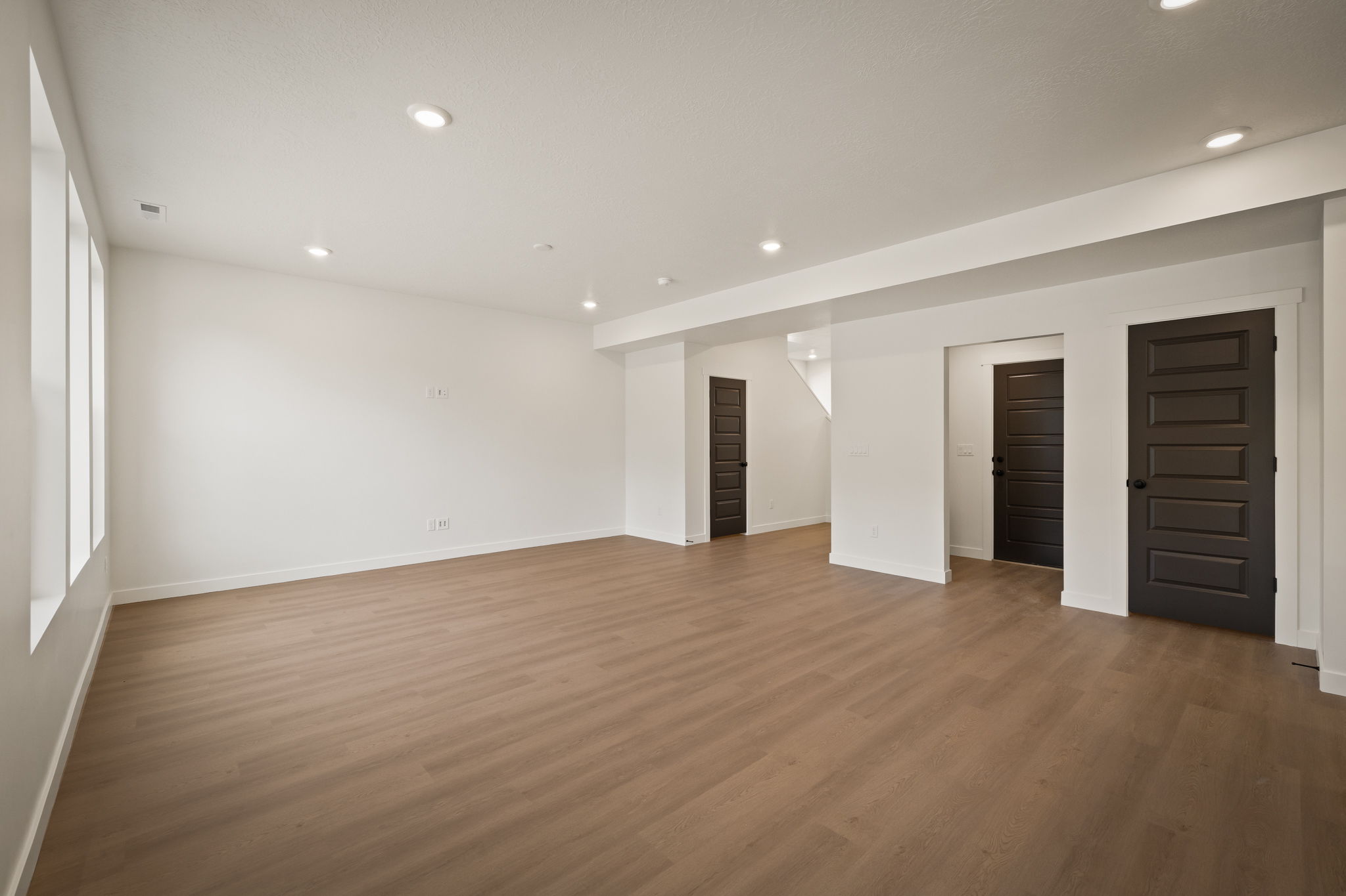 Spacious room featuring wood-finish flooring, recessed lighting, and multiple windows