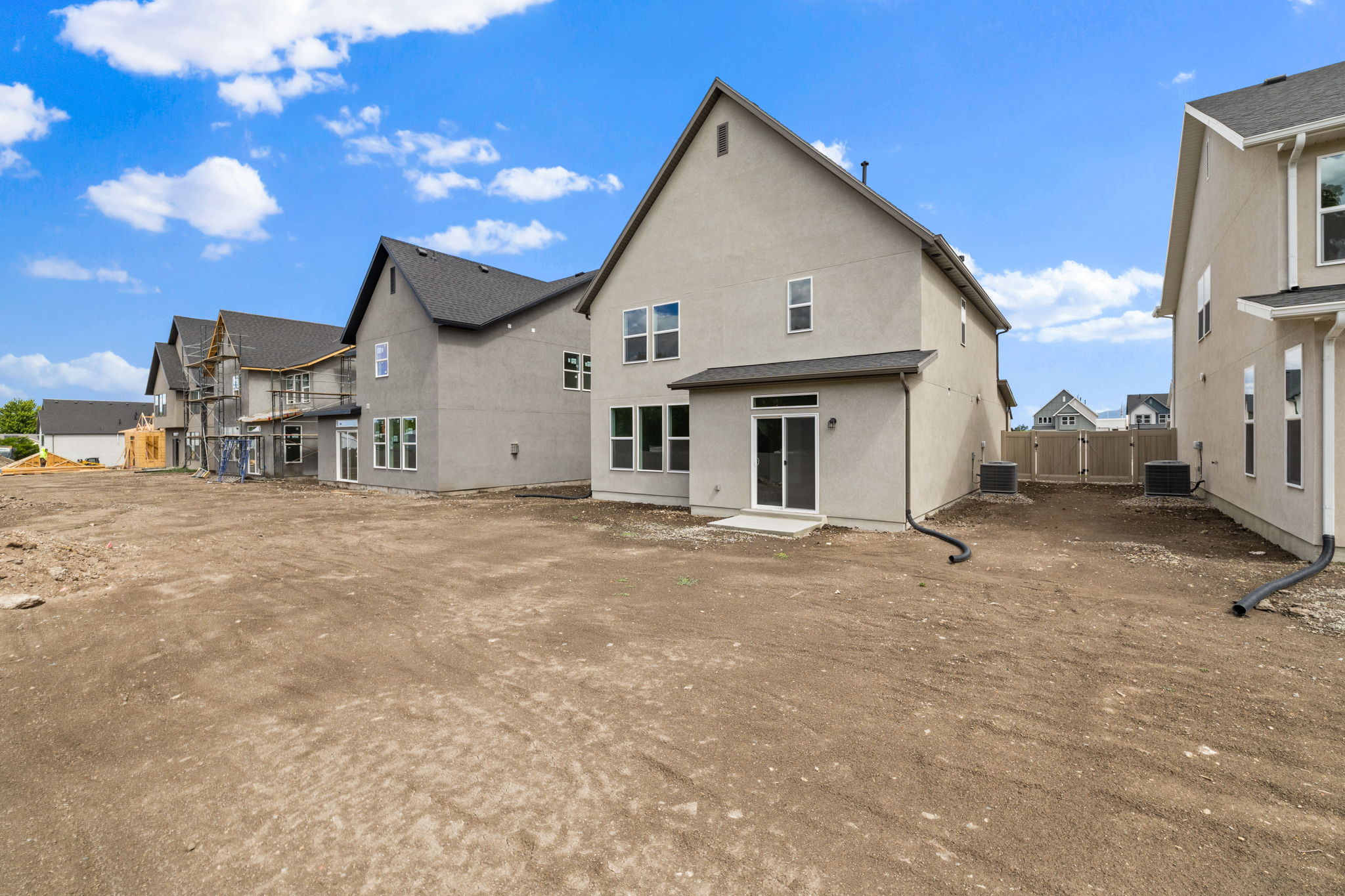 Rear elevation with a concrete patio, sliding glass door, and multiple windows