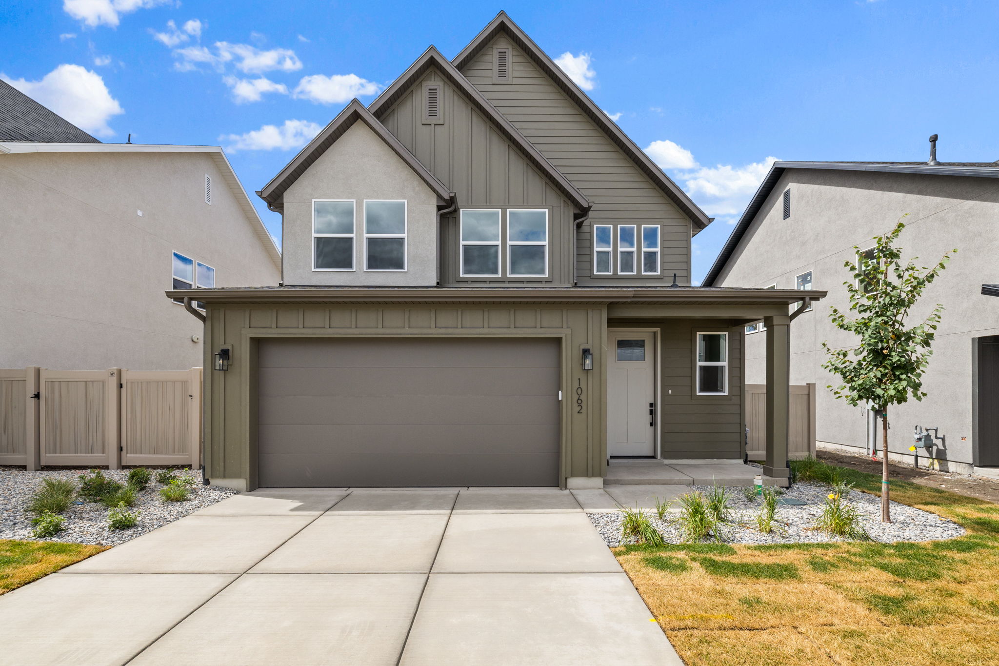 Contemporary two-story exterior with board and batten siding, attached two-car garage, covered front porch, and concrete driveway