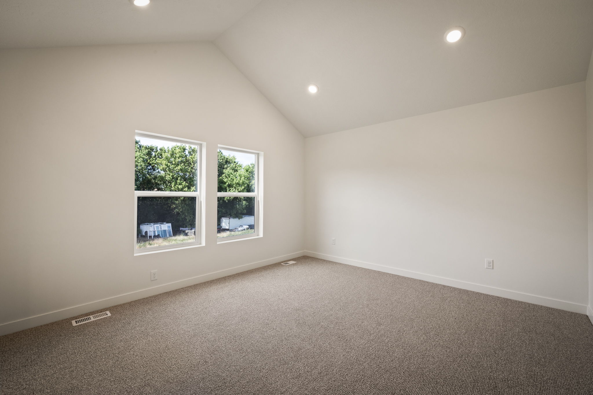Carpeted room featuring a vaulted ceiling with recessed lighting