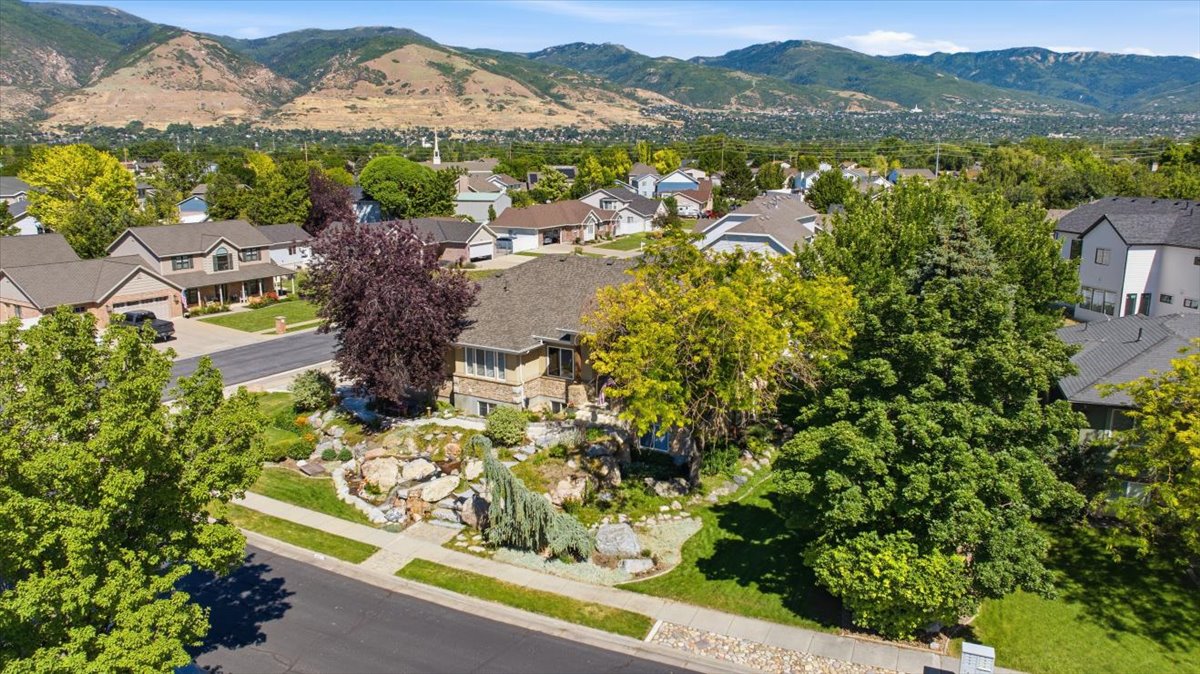 Hillside property featuring mature landscaping, a stone facade, and a multi-level rock garden with established plantings