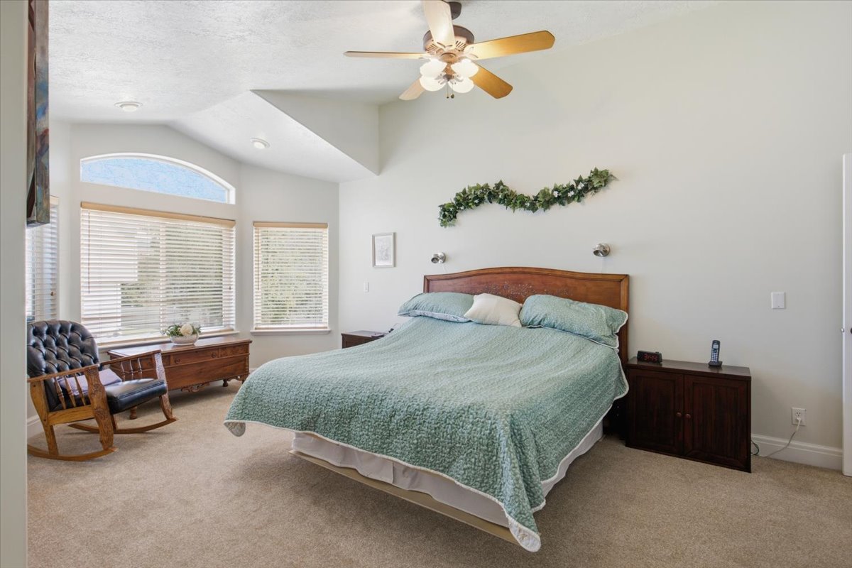 Spacious bedroom featuring vaulted ceilings, a ceiling fan with integrated lighting, recessed lighting, and expansive windows with blinds