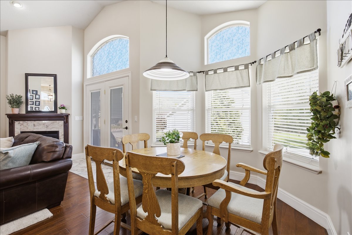 Vaulted ceilings above a dining area featuring wood-finish flooring and a contemporary pendant light fixture
