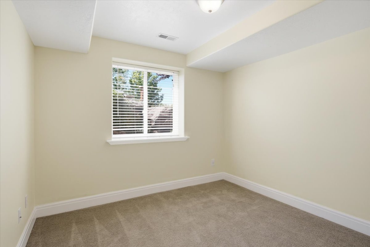 Carpeted room with a single window featuring white blinds, white trim, and light beige walls