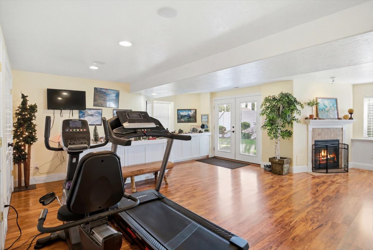 Spacious room featuring wood-finish flooring, recessed lighting, and a corner fireplace with a tiled surround and mantel