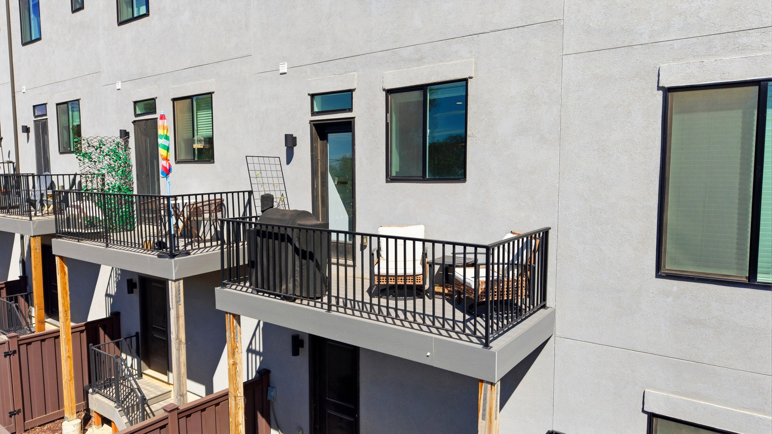 Private balcony featuring dark metal railings and a textured exterior finish