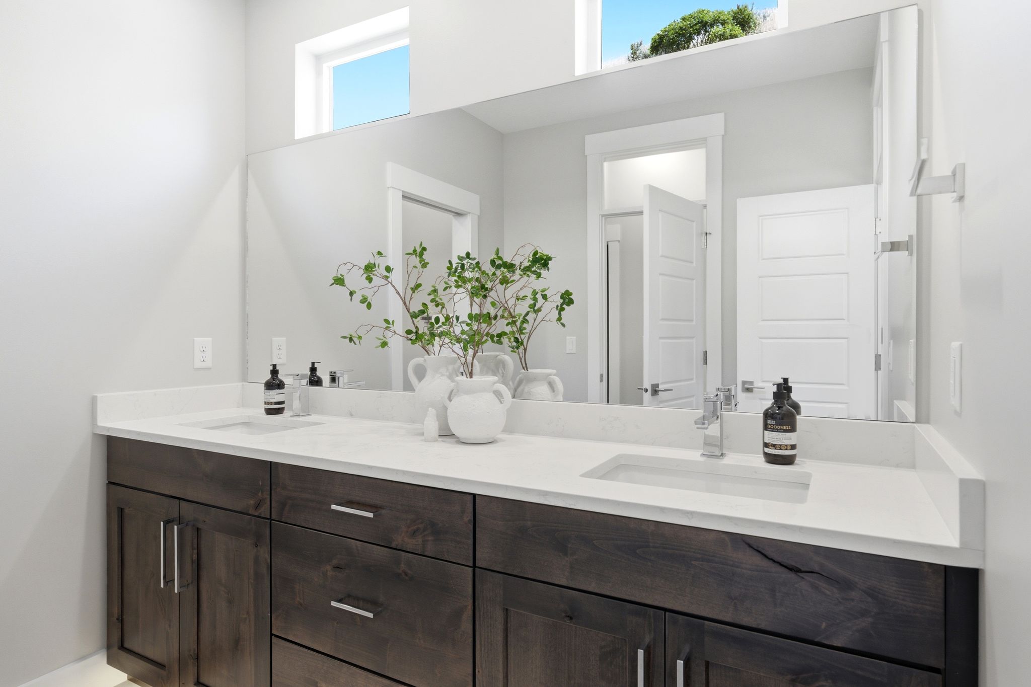 Dual vanity featuring dark wood-finish cabinetry, white stone countertops, and integrated rectangular sinks