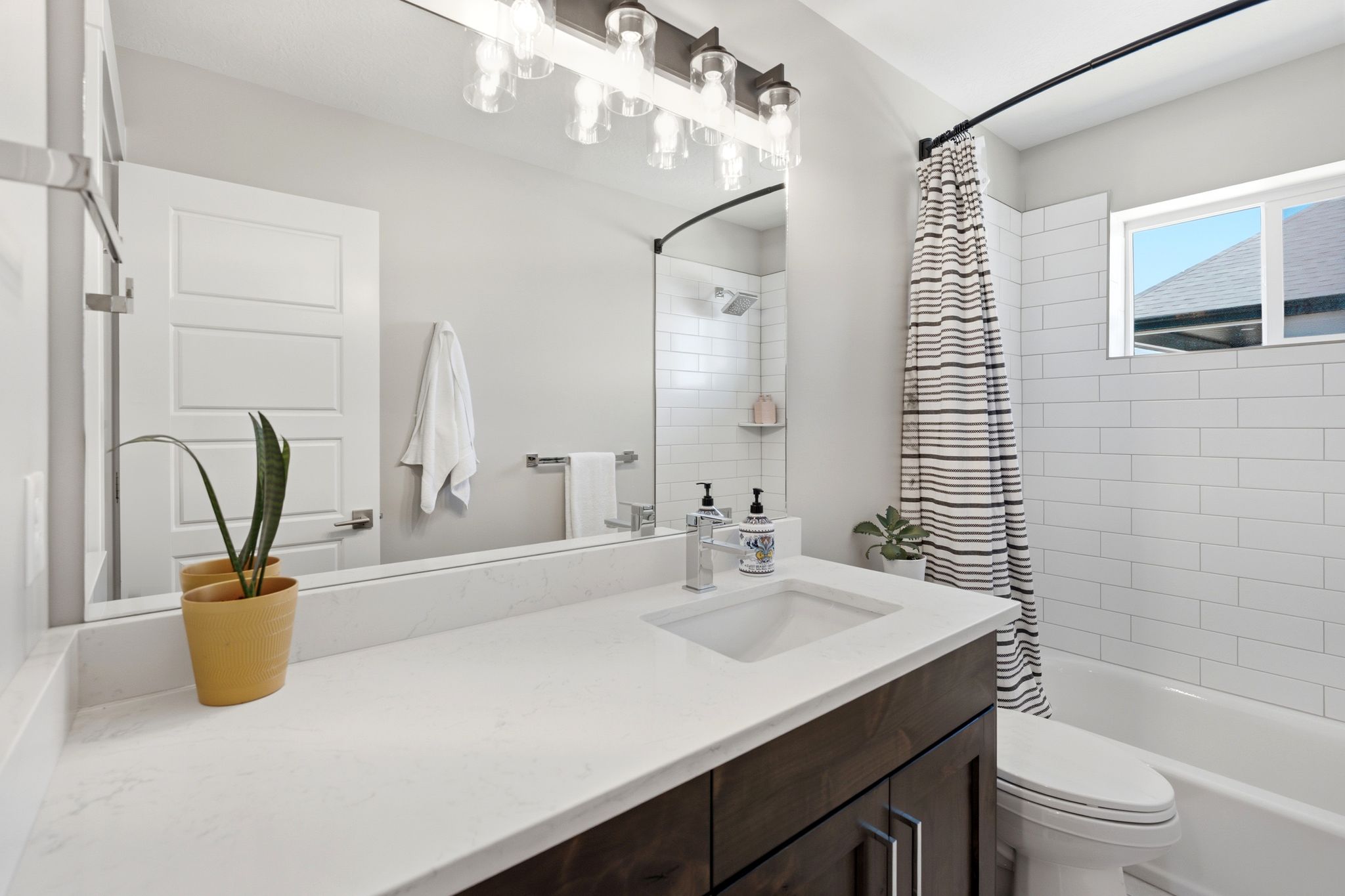 Bathroom featuring a dark wood-finish vanity with a light countertop, an undermount sink, and a chrome faucet