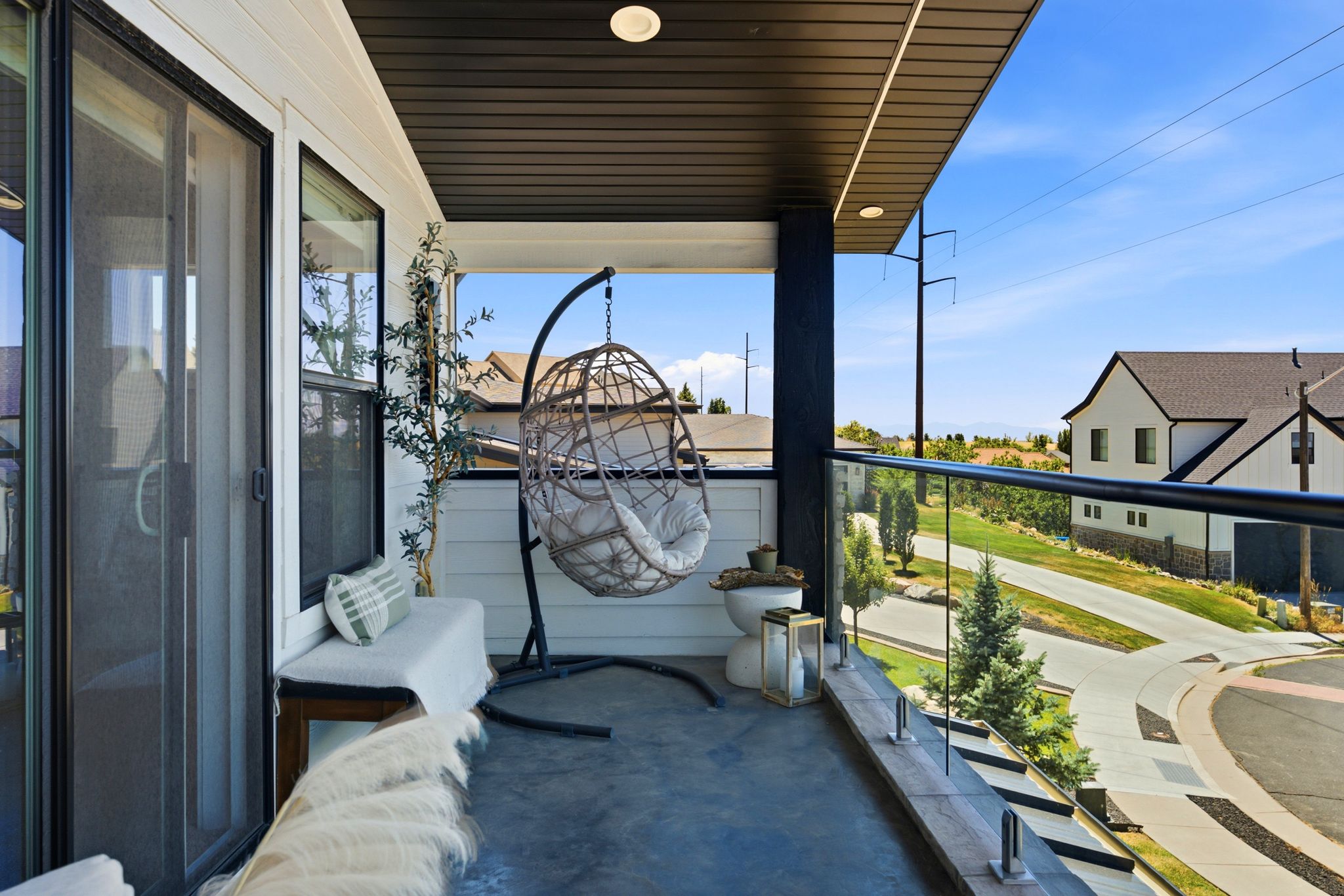 Balcony featuring glass panel railing, a durable concrete floor, and a black beam accent
