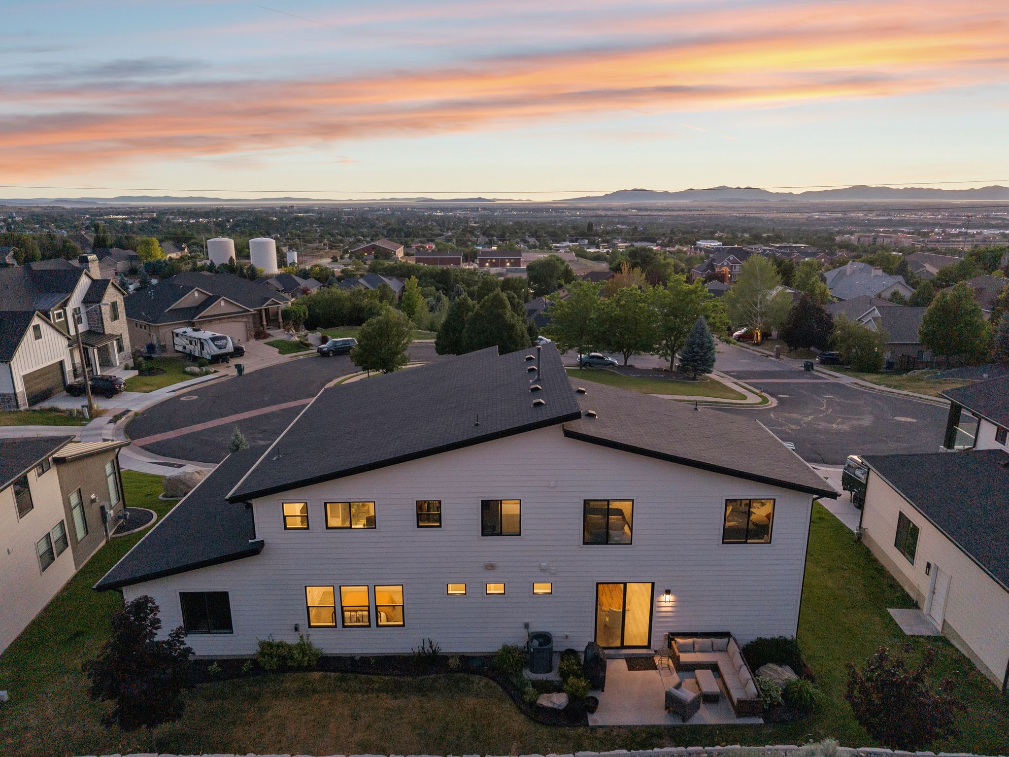 Contemporary residence featuring a white siding exterior, dark framed windows, and a dark shingle roof