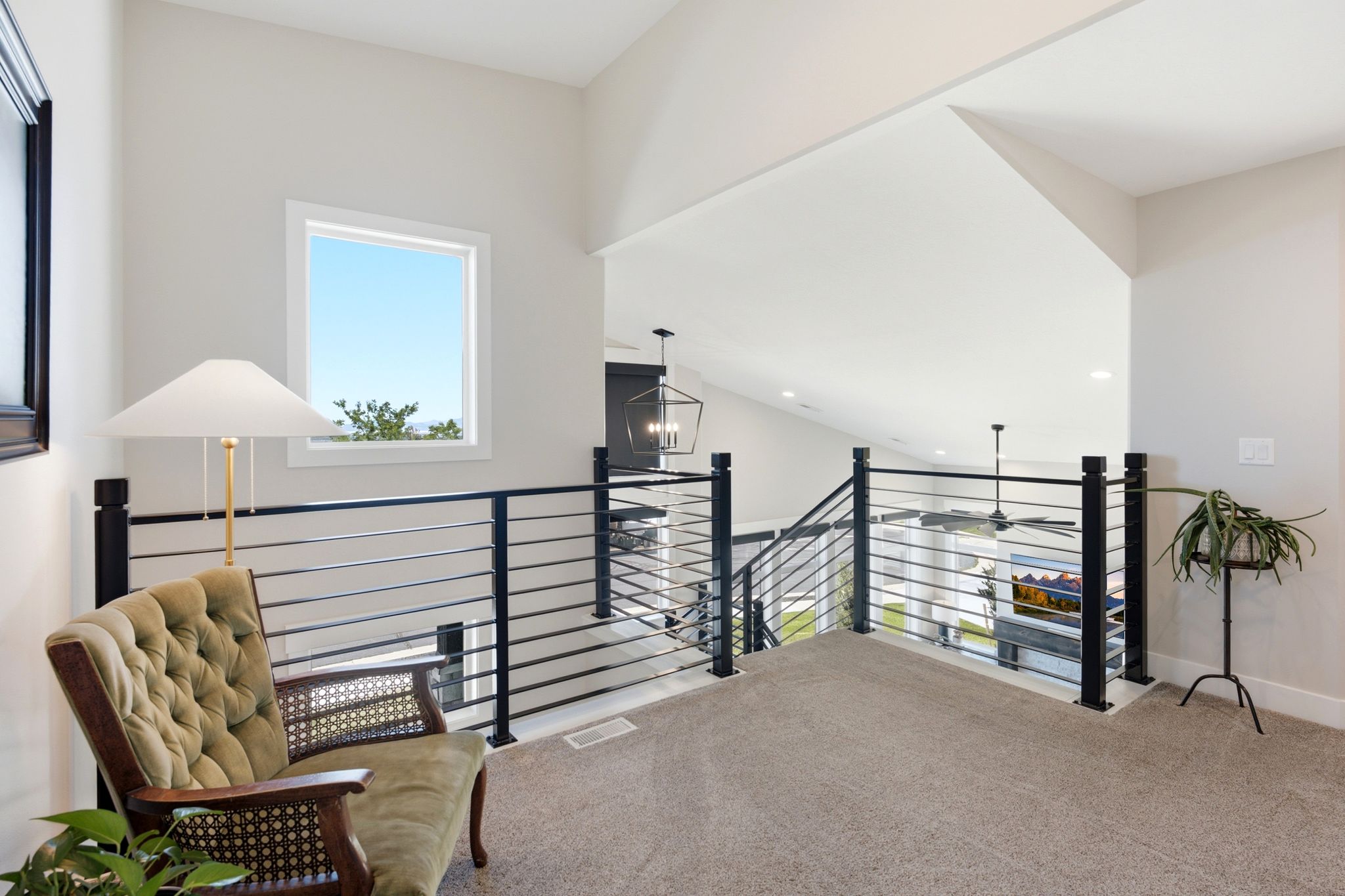 Upper-level landing featuring a contemporary horizontal bar railing, vaulted ceilings, and a window with exterior visibility