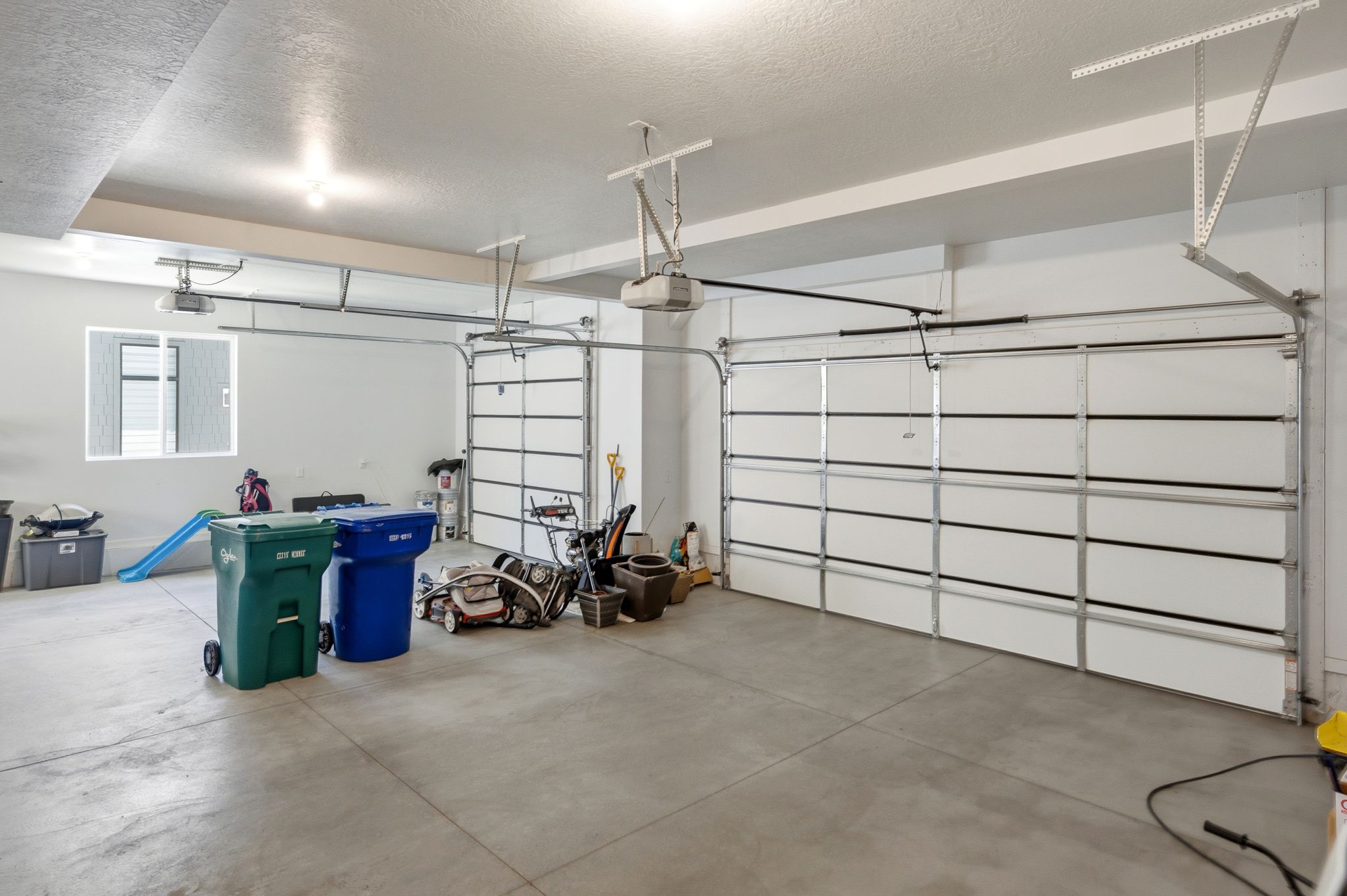 Spacious two-car garage featuring a concrete floor, two automatic garage door openers, and a window