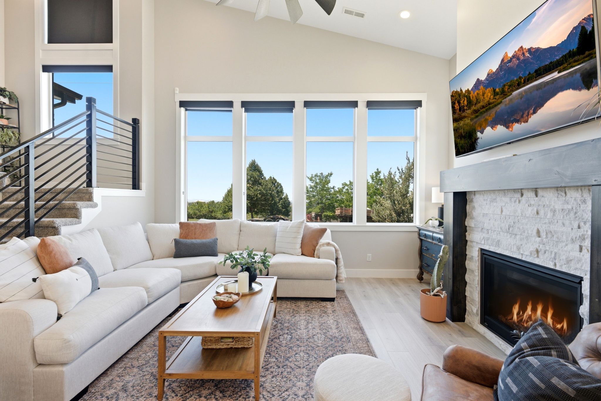 Living area featuring a stone-clad fireplace with a dark wood mantle, wood-finish flooring, and high vaulted ceilings