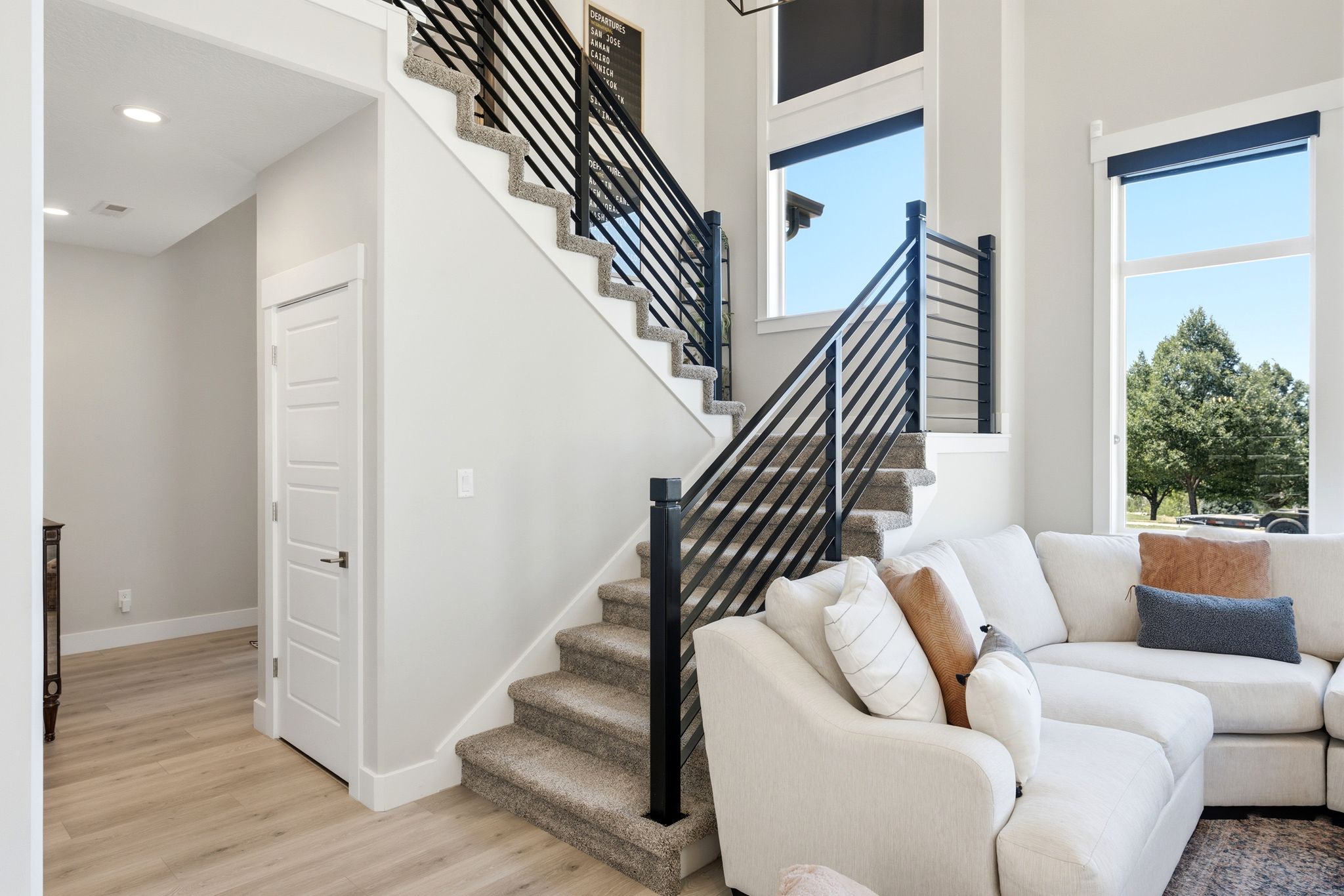 Two-story entryway featuring a modern black horizontal bar stair railing and light wood-finish flooring