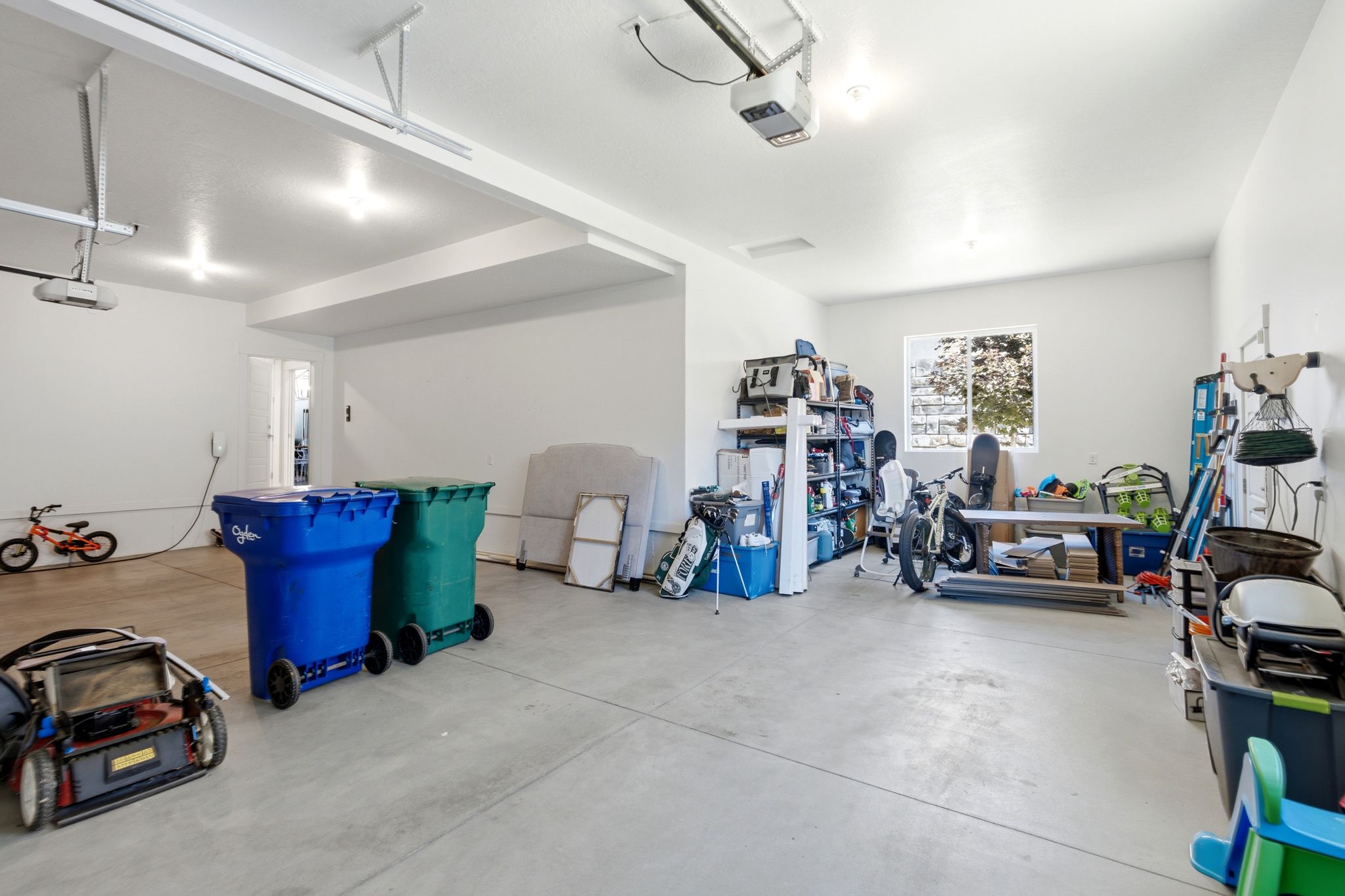 Spacious garage featuring a concrete floor, bright white walls, and an overhead garage door opener