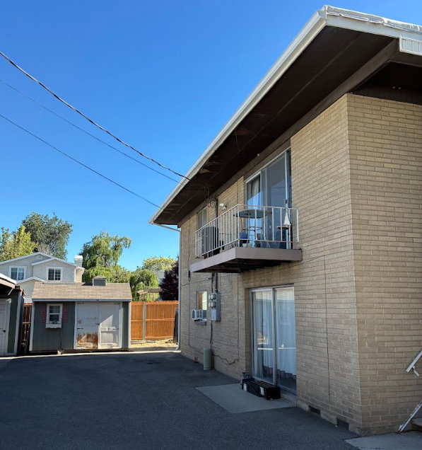 Brick exterior featuring a private balcony with metal railing, sliding glass doors, and a window-mounted air conditioning unit