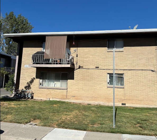 Two-story brick exterior building featuring an upper-level balcony with metal railing
