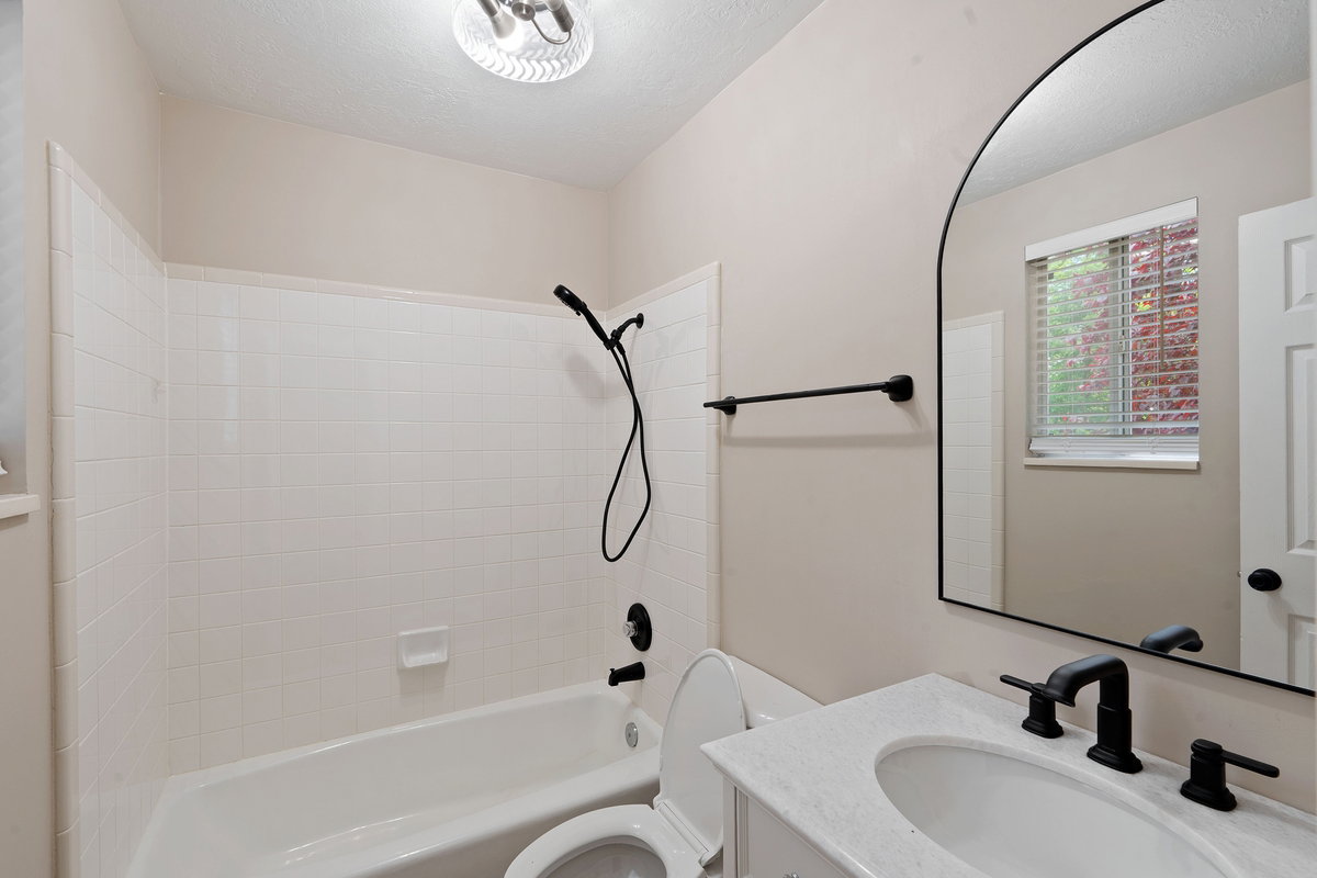 Bathroom featuring a white vanity with a white countertop, undermount sink, and matte black fixtures