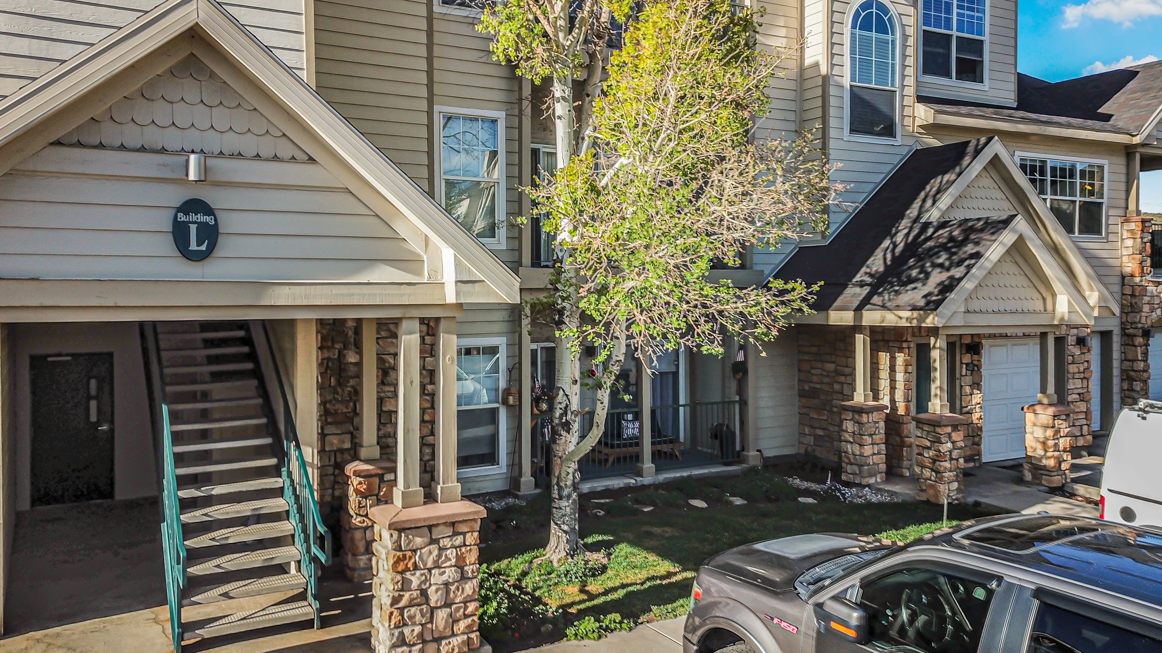 Multi-level building exterior featuring stone veneer accents, light-toned siding, and a prominent gable roofline