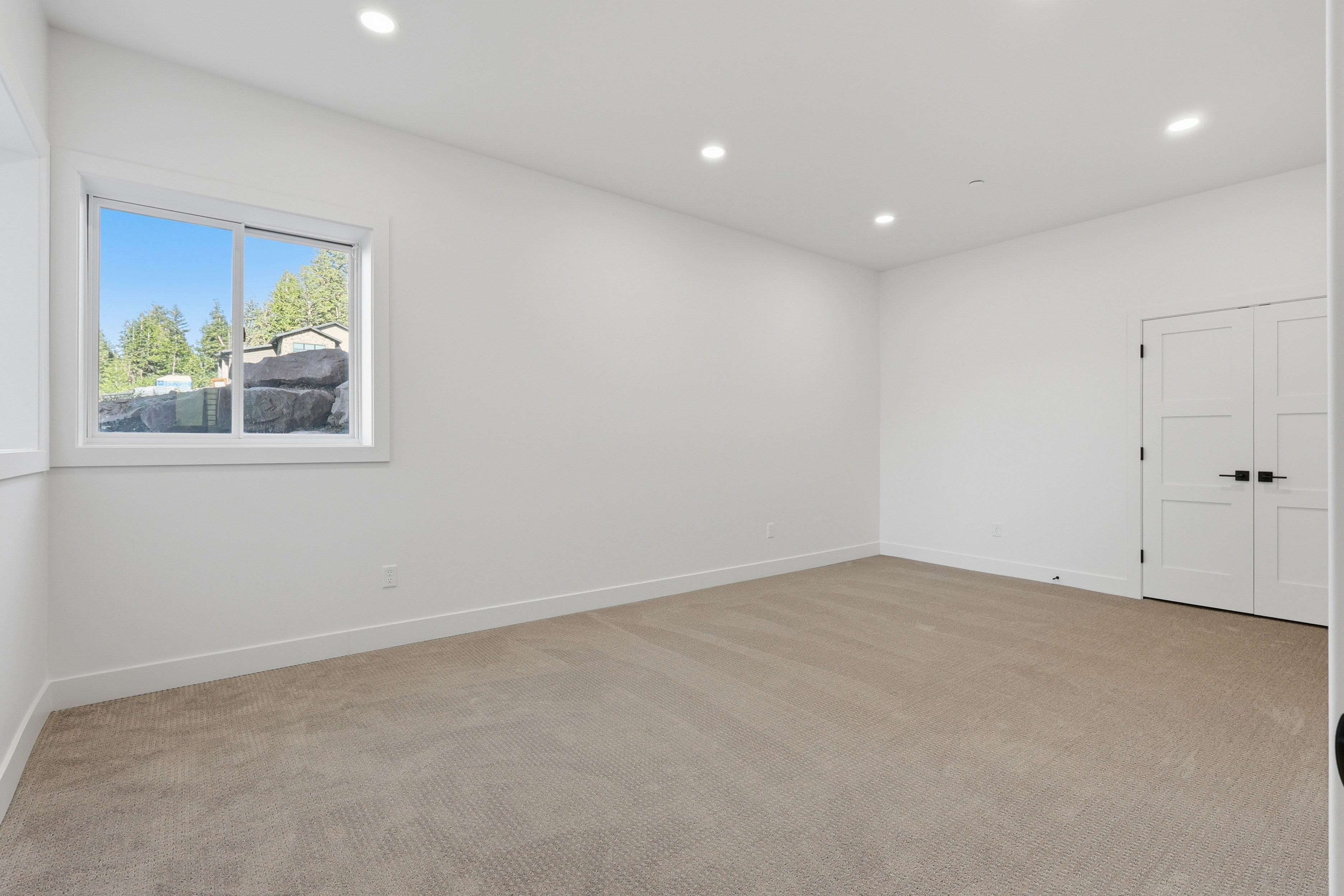 Spacious room featuring neutral carpeting, recessed lighting, and a white-framed window