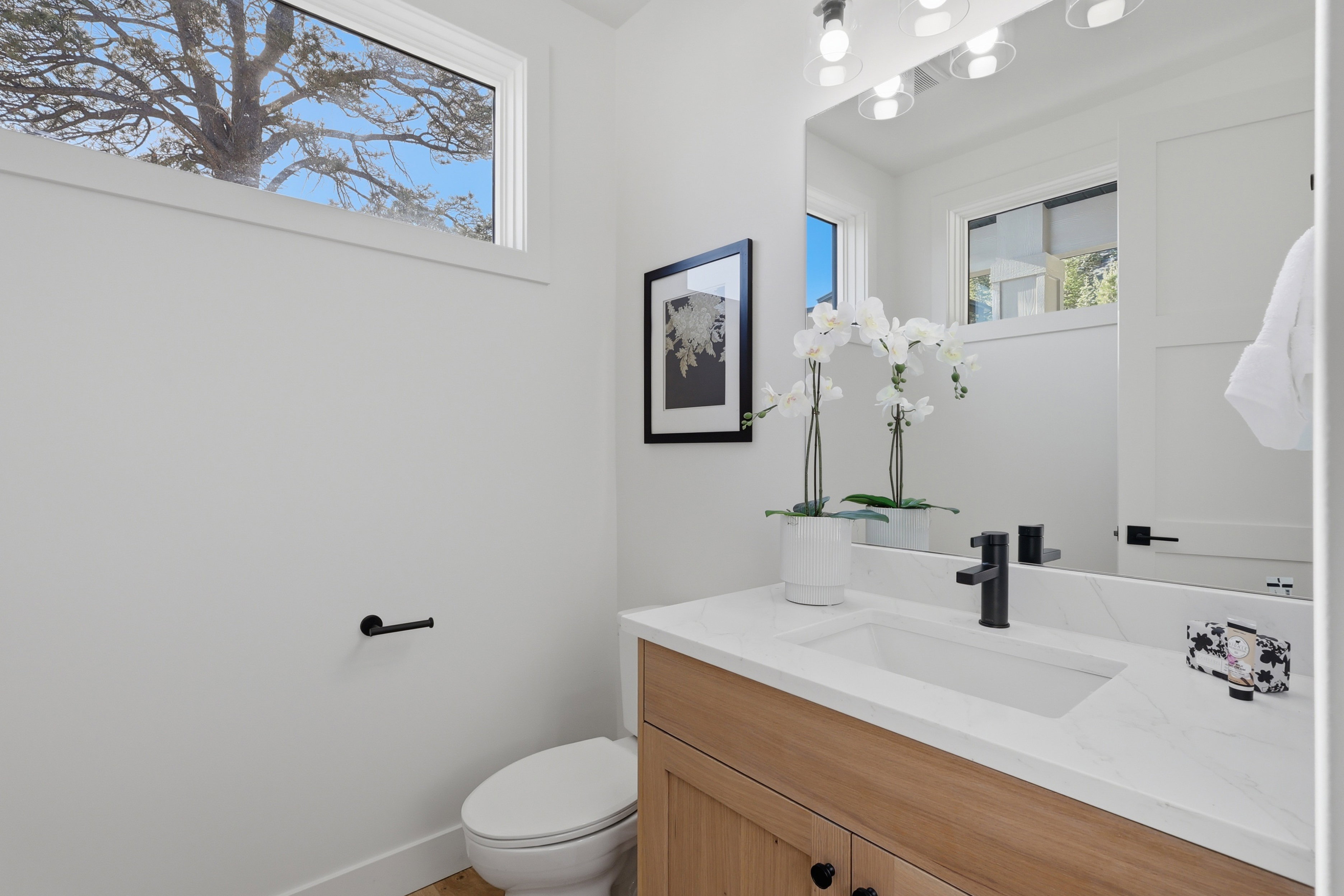 Modern bathroom featuring a wood-finish vanity with a white countertop and integrated sink