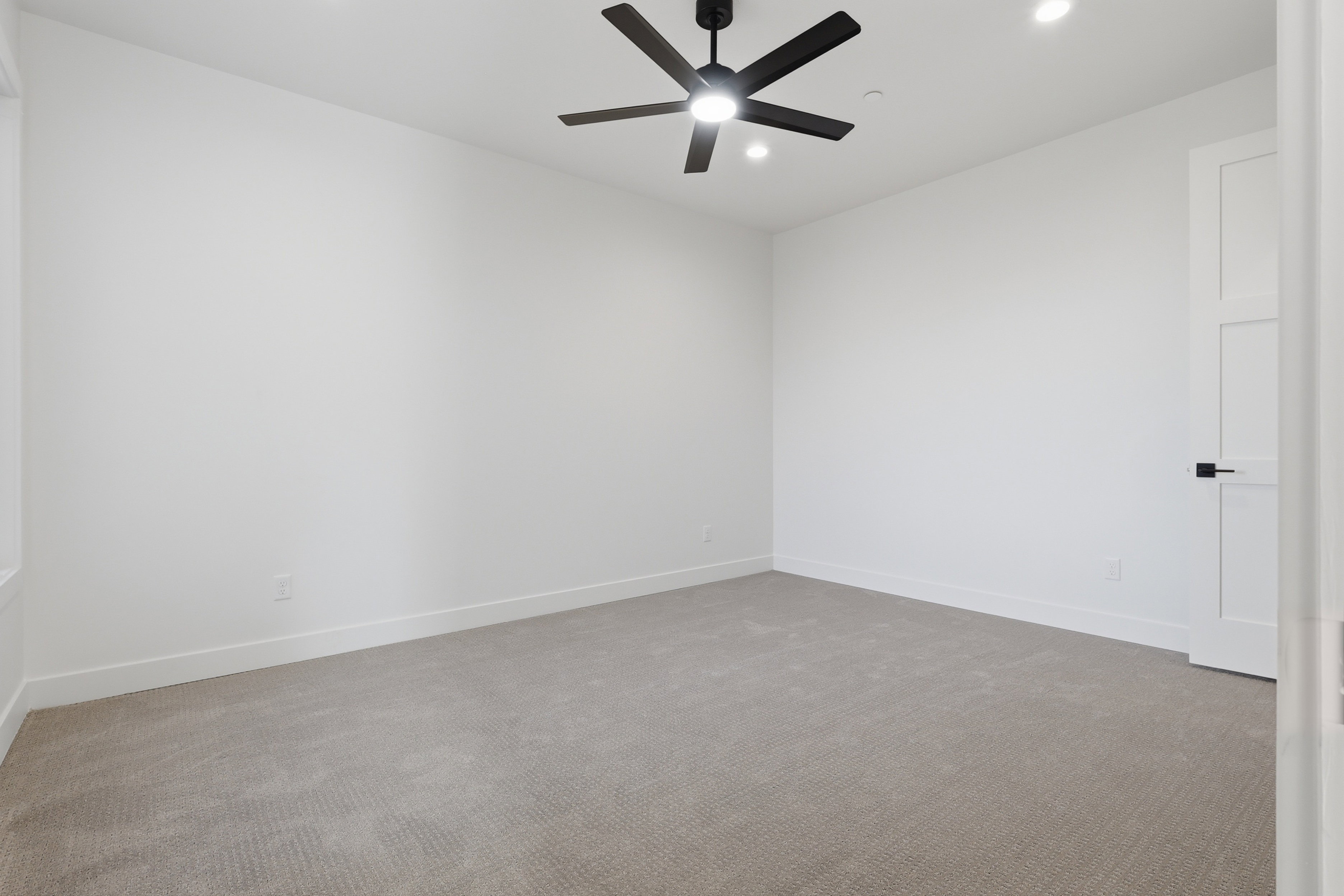 Carpeted room featuring a ceiling fan with integrated lighting, recessed lighting, white walls, and a modern interior door with black hardware