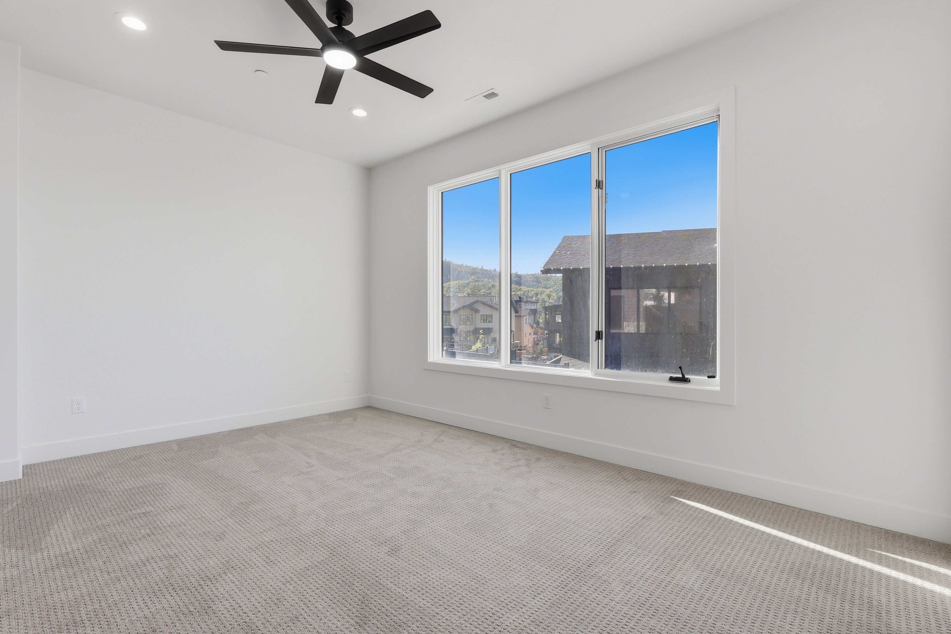 Bright room featuring a large window with multiple panes, recessed lighting, and a ceiling fan