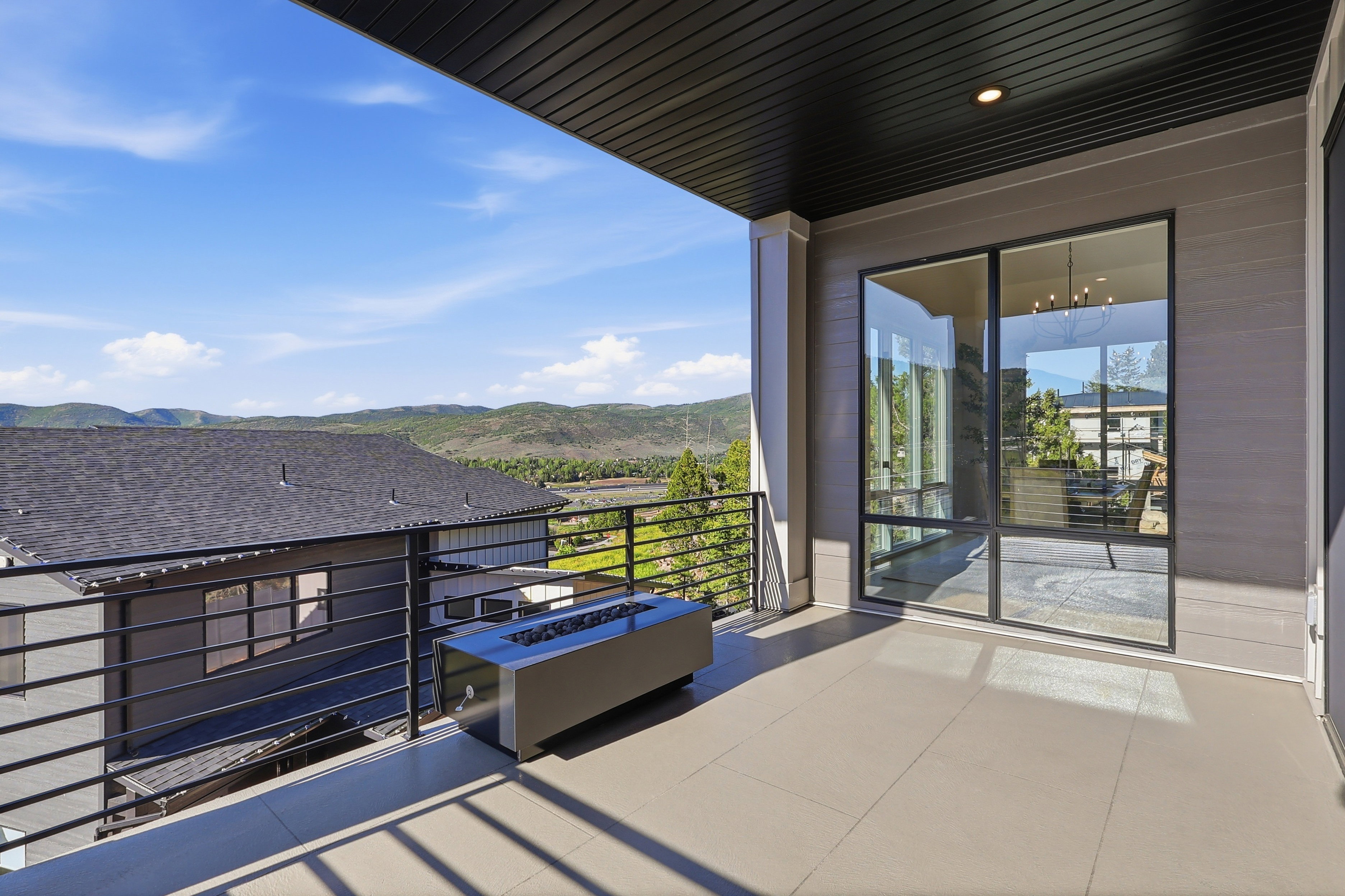 Expansive balcony featuring a linear fire pit, tile flooring, and a black metal railing