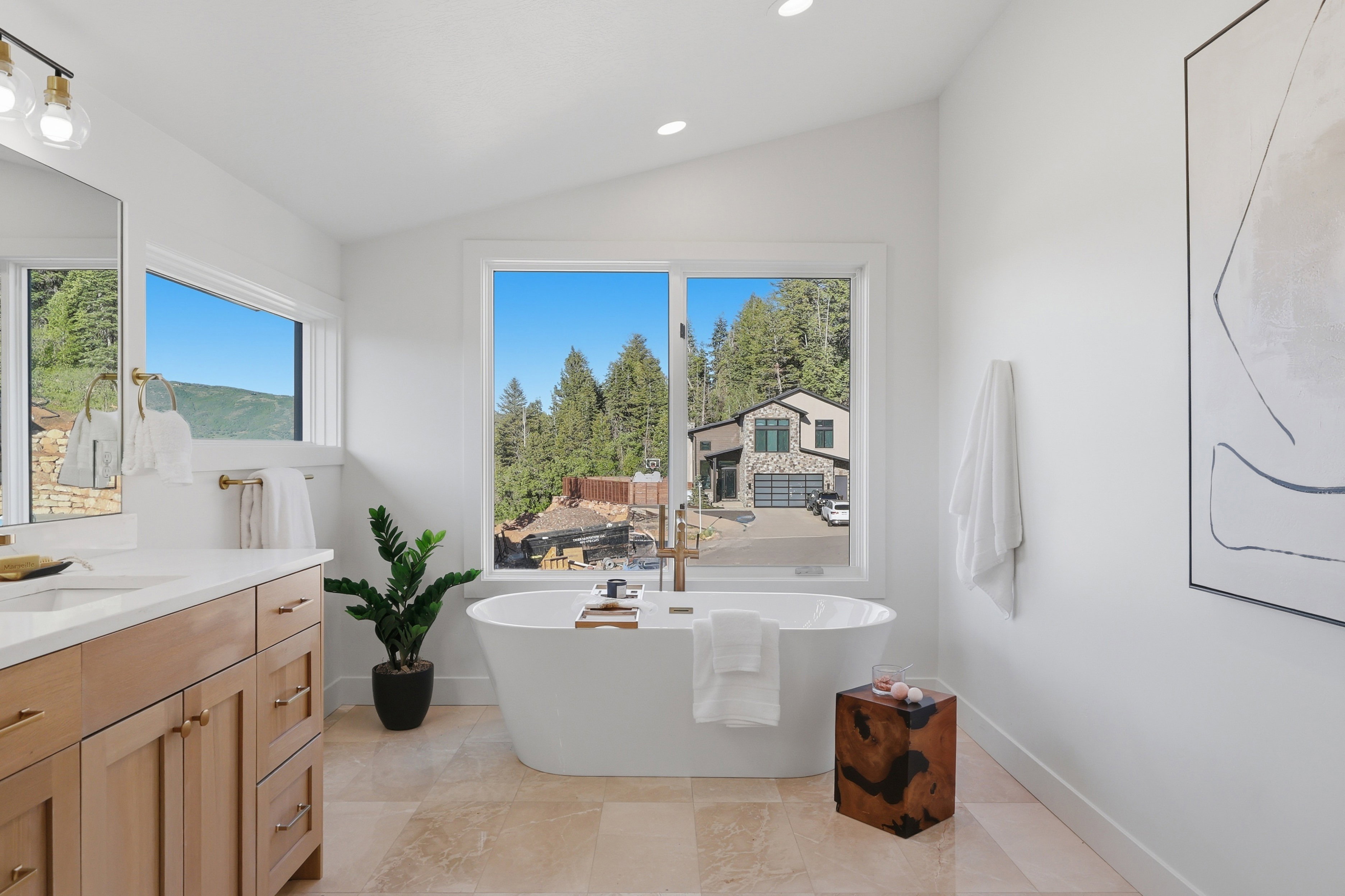 Freestanding soaking tub with gold-finish fixtures and surrounding windows