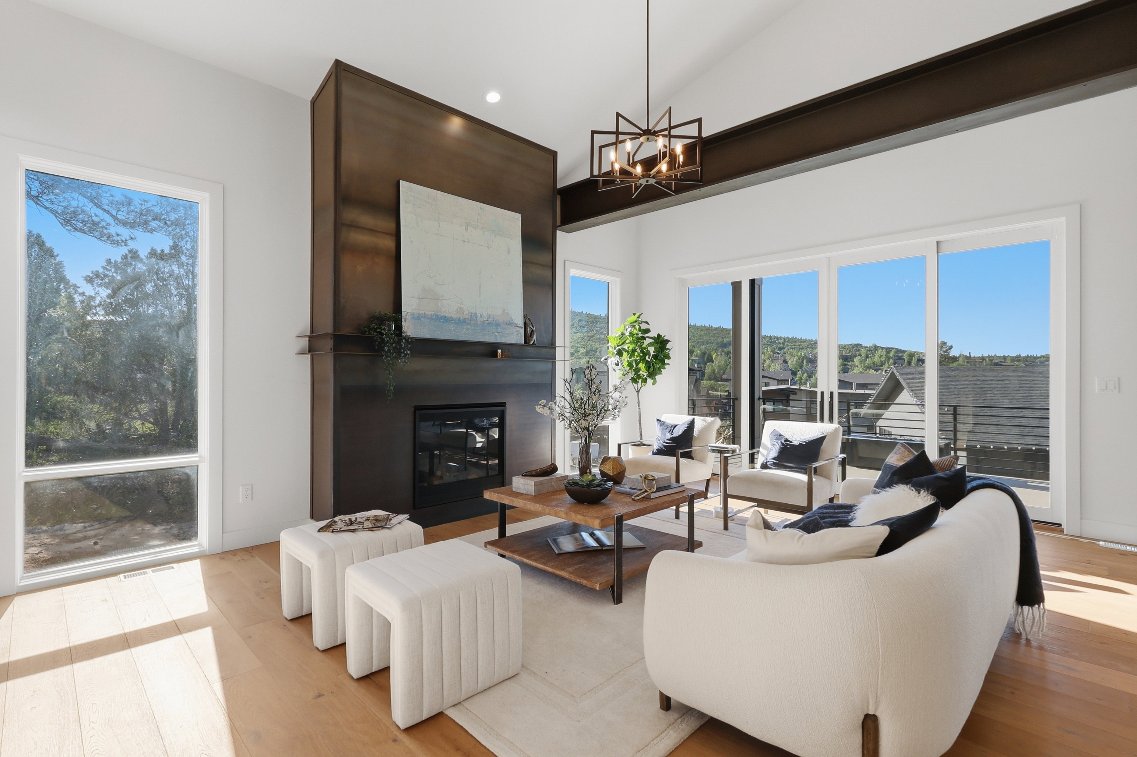 Vaulted ceiling living area featuring a prominent dark-toned fireplace surround, light wood-finish flooring, and large sliding glass doors opening to outdoor space