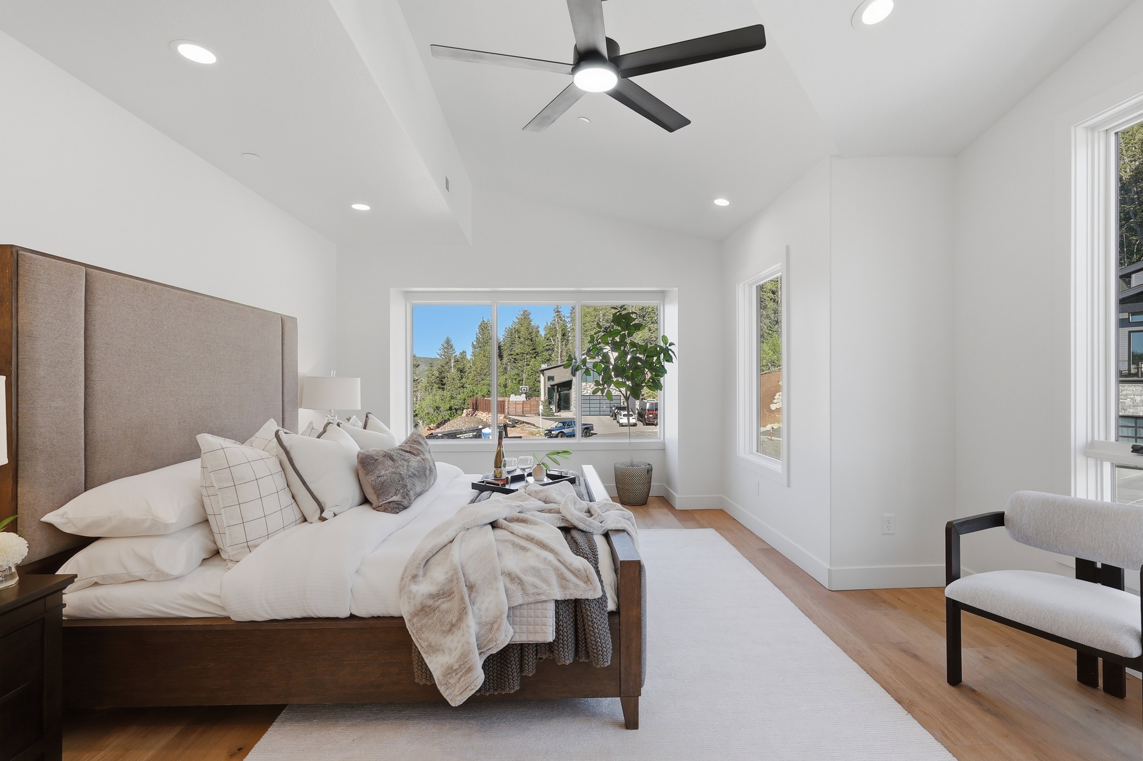 Spacious room featuring vaulted ceilings, recessed lighting, wood-finish flooring, and multiple large windows