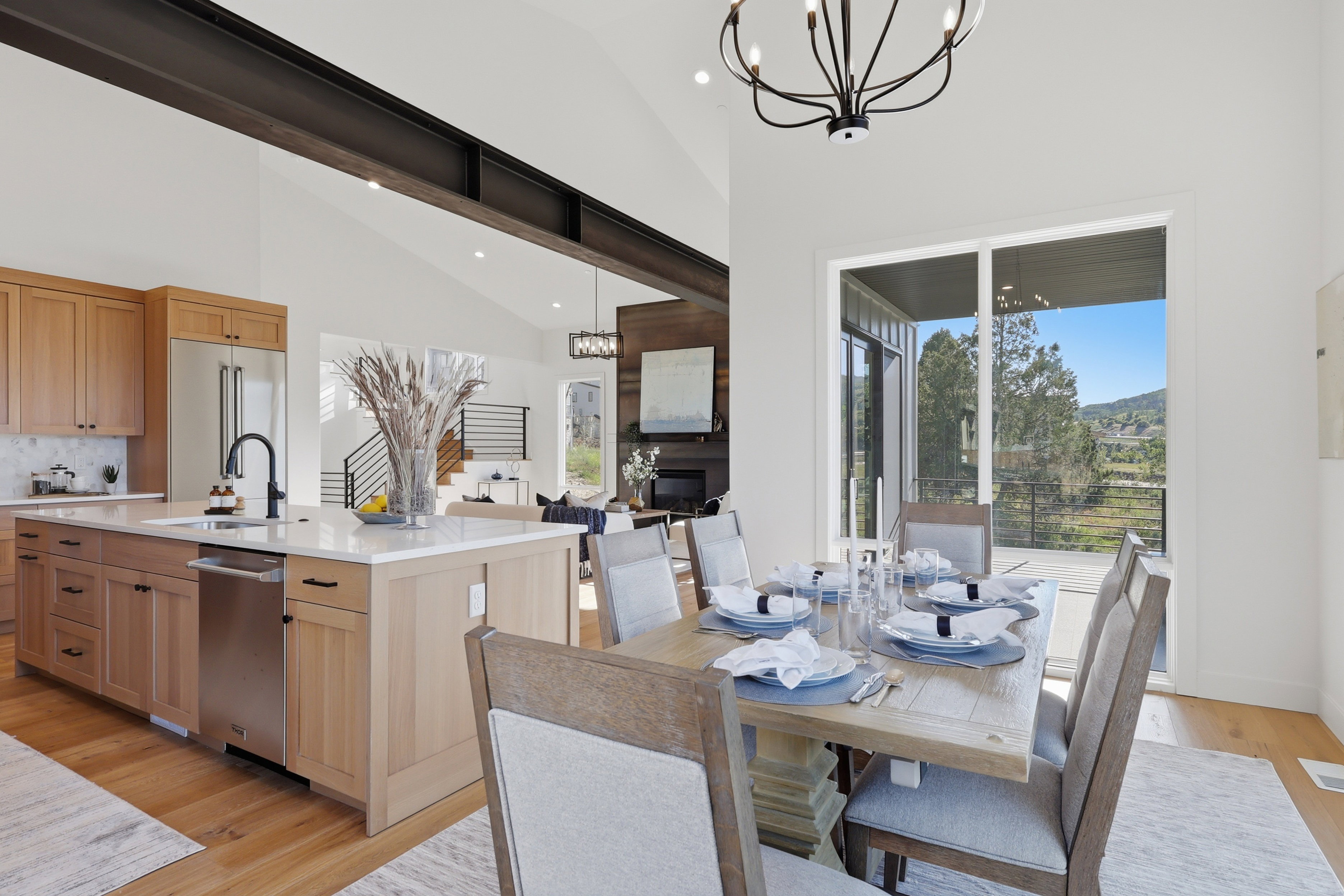 Open-concept dining area featuring a sliding glass door, a contemporary chandelier, vaulted ceilings, and engineered wood flooring