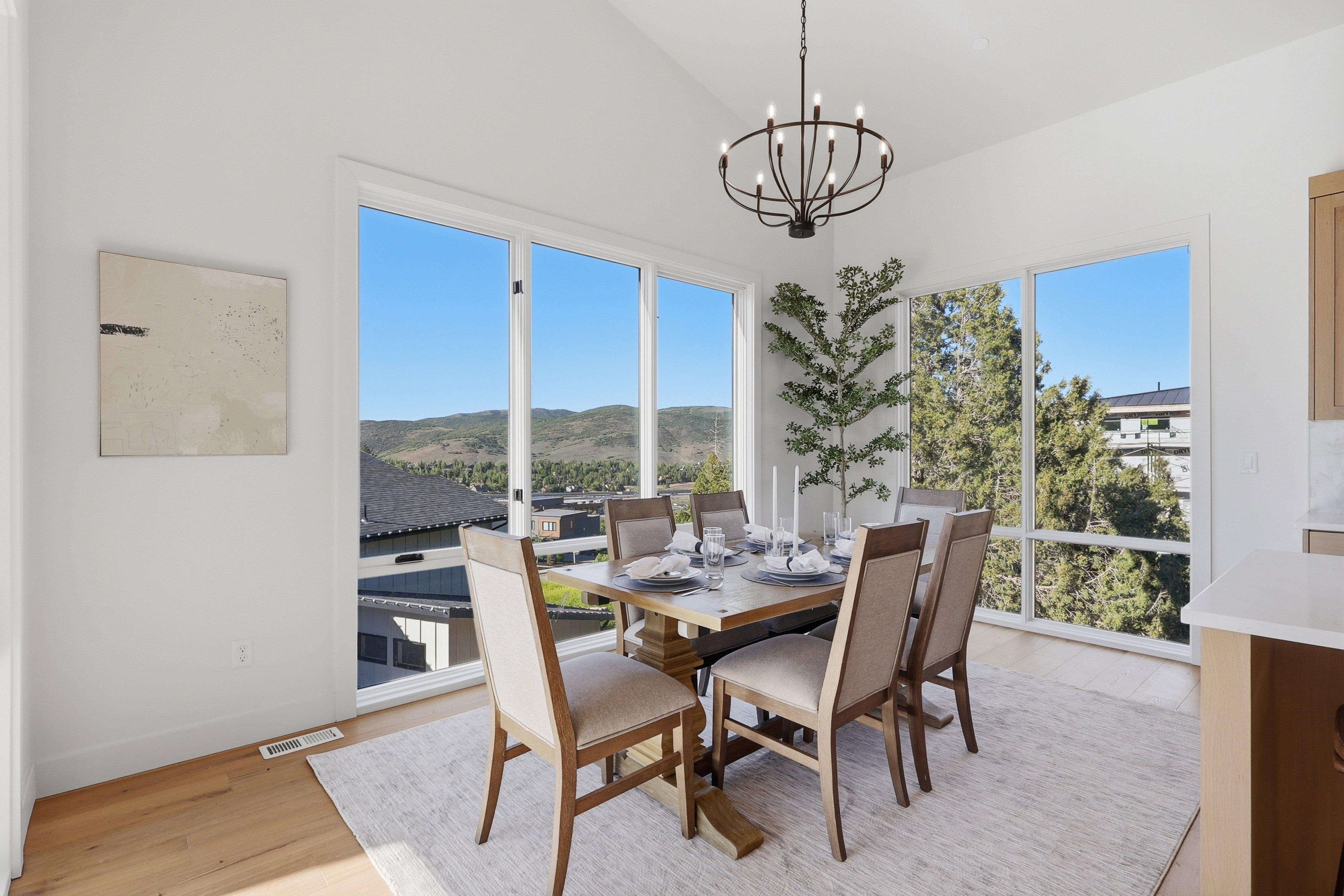 Dining area featuring expansive windows, wood-finish flooring, a vaulted ceiling, and a modern chandelier